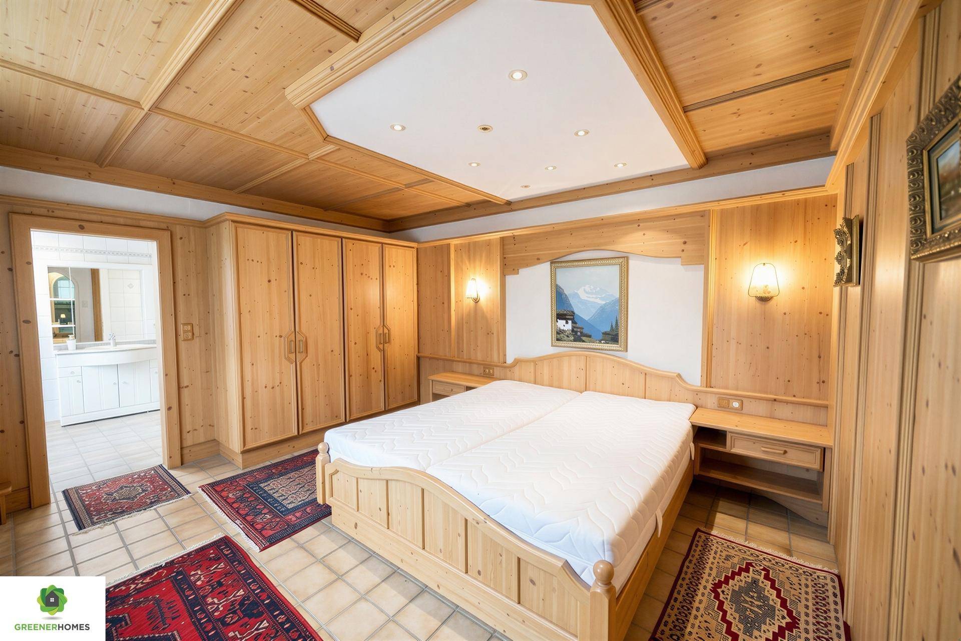 Helles Schlafzimmer mit Holzmöbeln, Einbauschränken und Zugang zu einem angrenzenden Badezimmer.