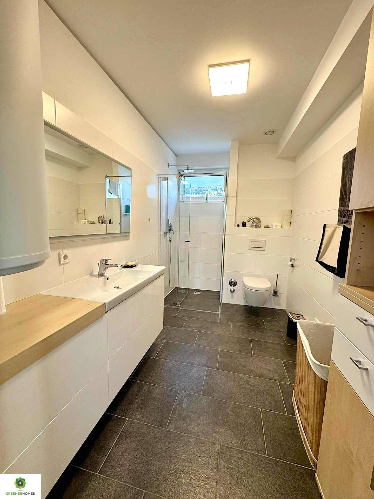 Modernes Badezimmer mit großformatigen Fliesen, begehbarer Dusche und elegantem Waschtisch.