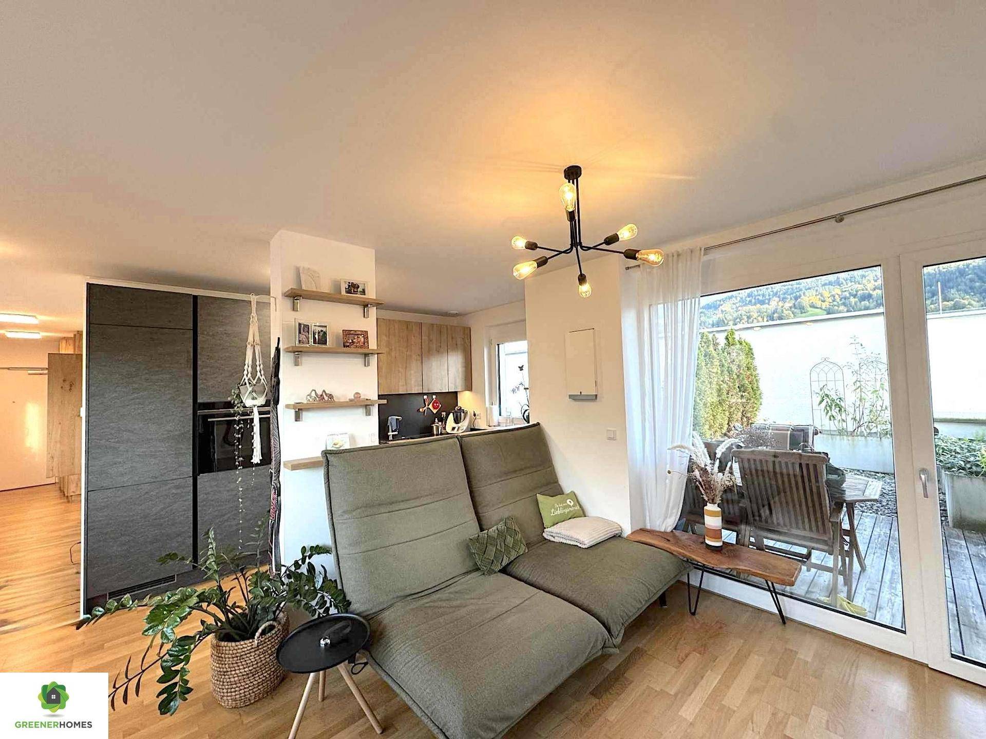 Heller Wohnbereich mit bequemer Couch und Zugang zu einer großzügigen Terrasse.