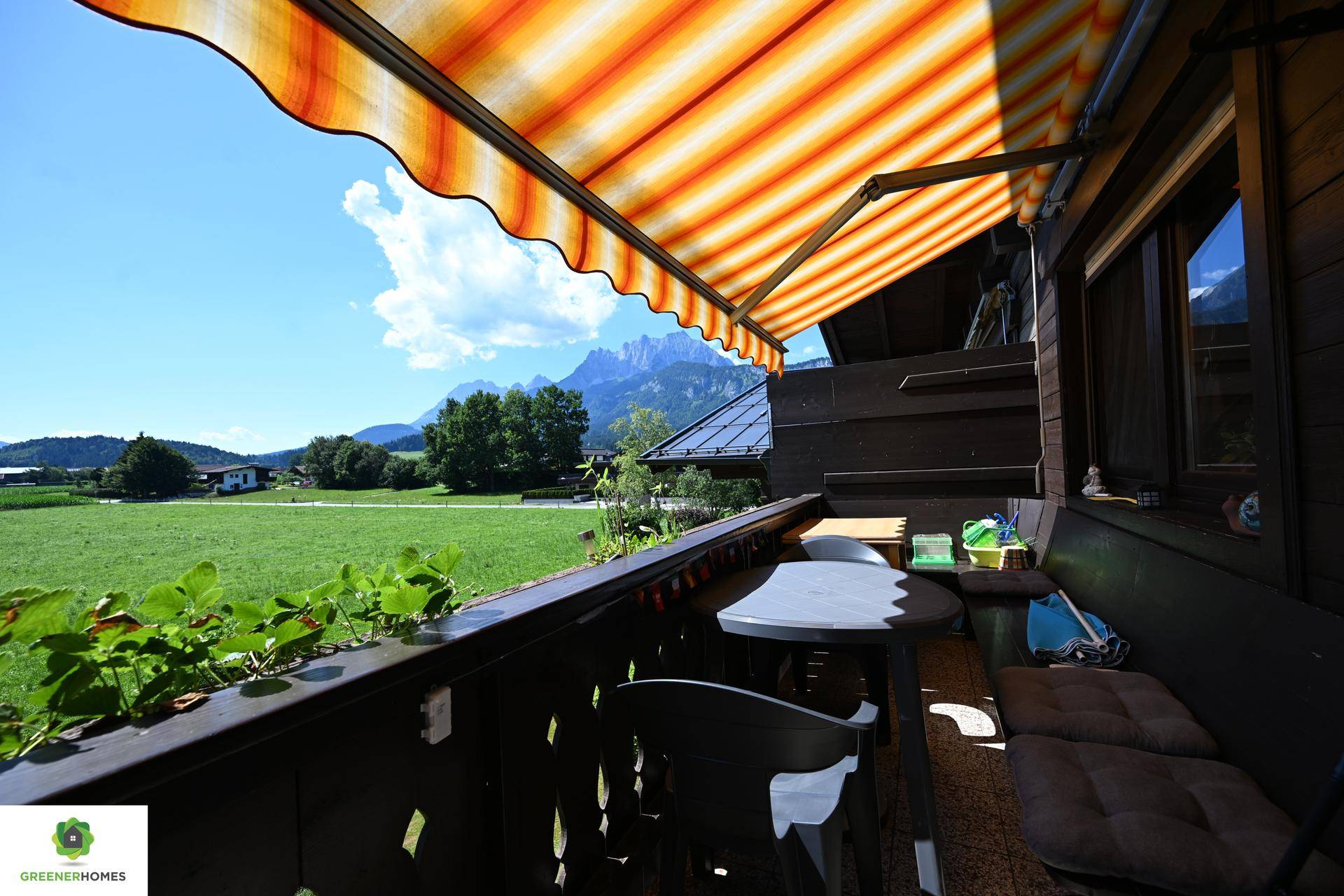 Balkon mit gestreifter Markise, Sitzgelegenheiten und weitem Blick auf die ländliche Landschaft.