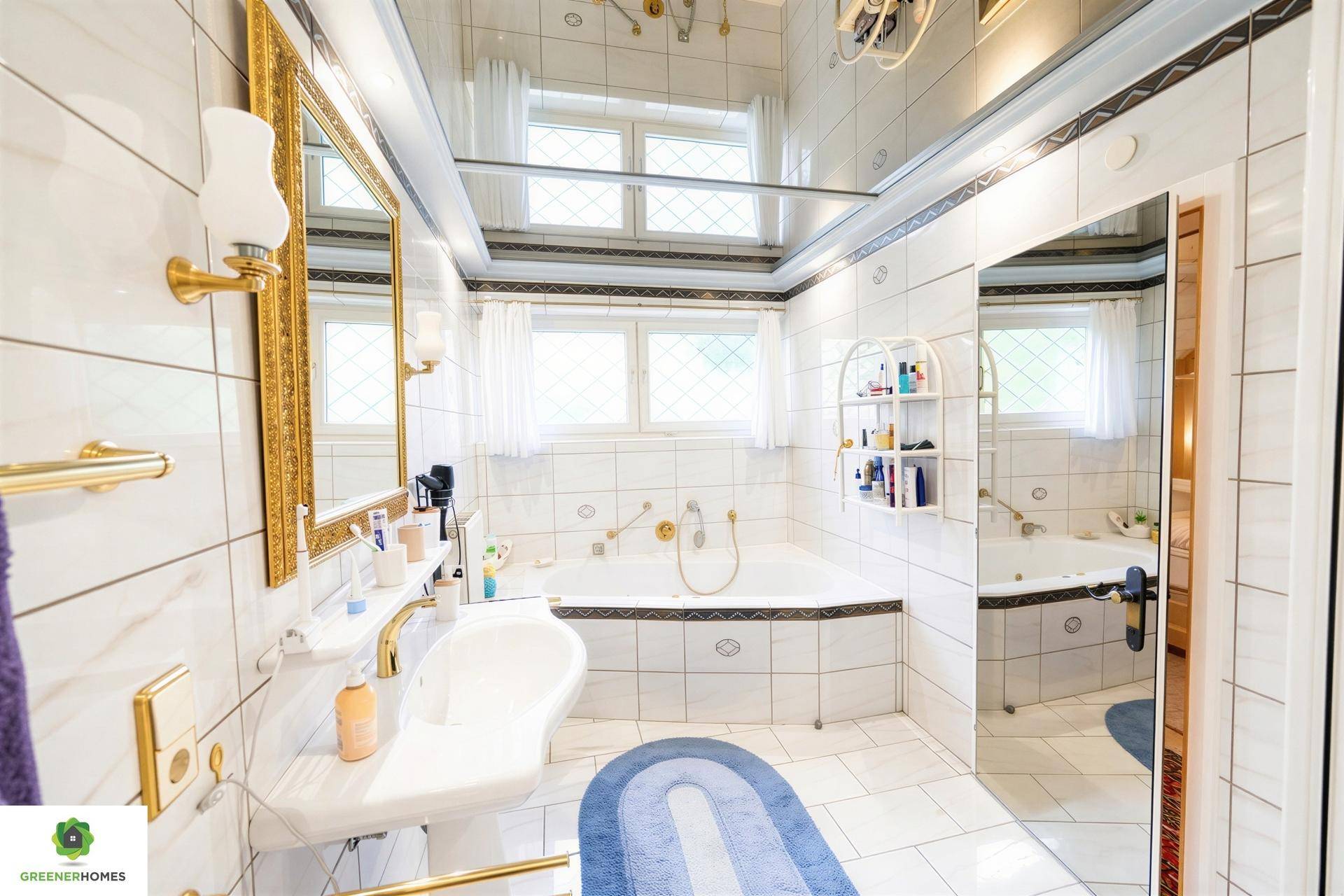 Helles Badezimmer mit weißen Fliesen, Badewanne und goldenen Armaturen im klassischen Stil.