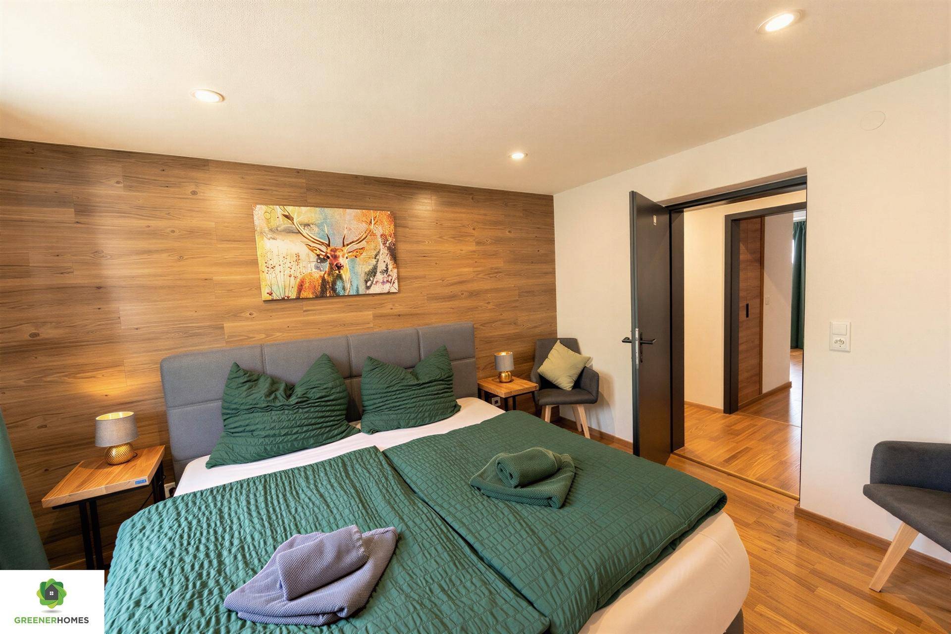 Schlafzimmer mit Holzwand, Doppelbett und offenem Zugang zu einem weiteren Raum.
