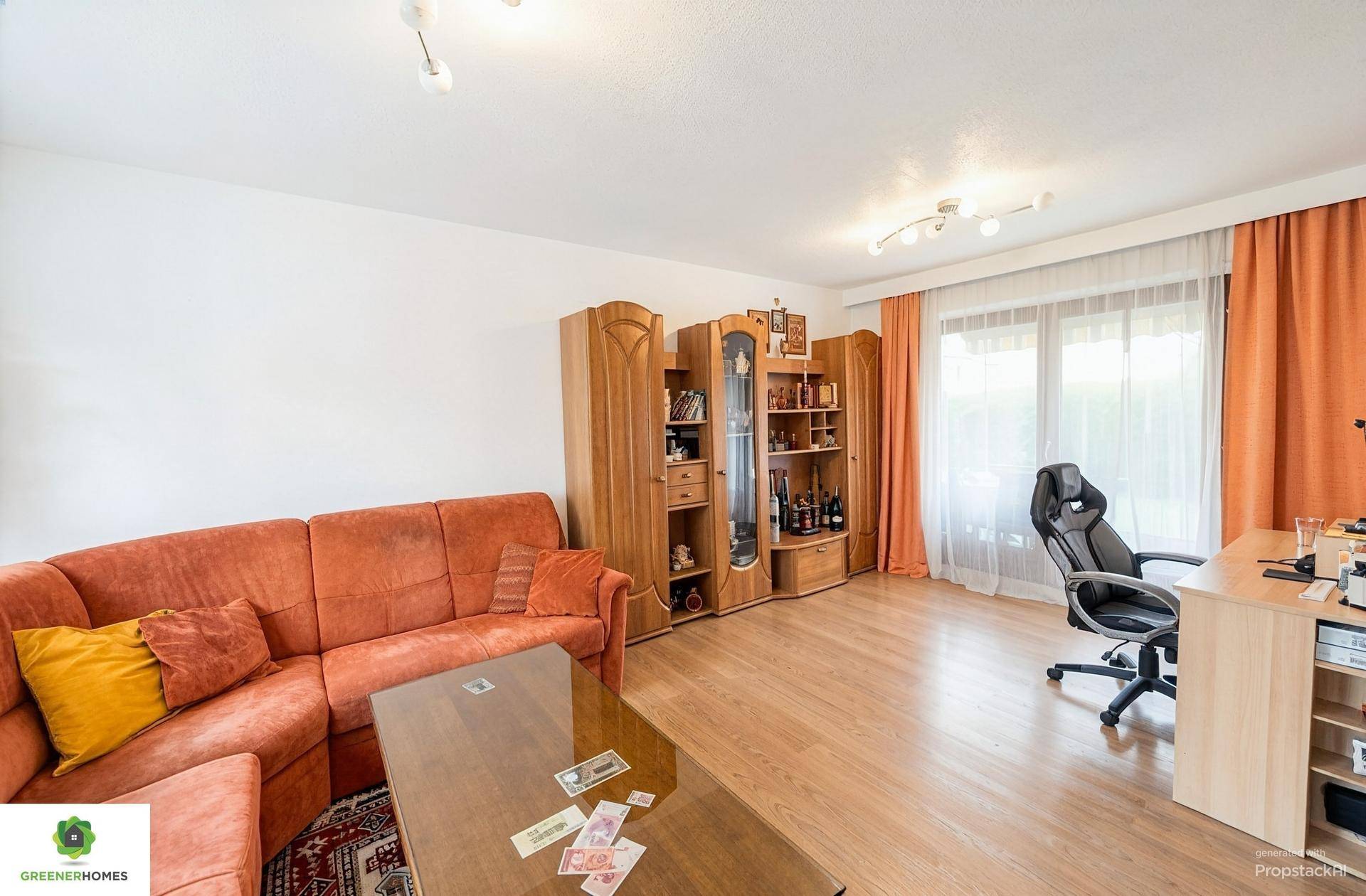 Geräumiges Wohnzimmer mit traditionellen Holzschränken, orangefarbenem Sofa und Schreibtisch.