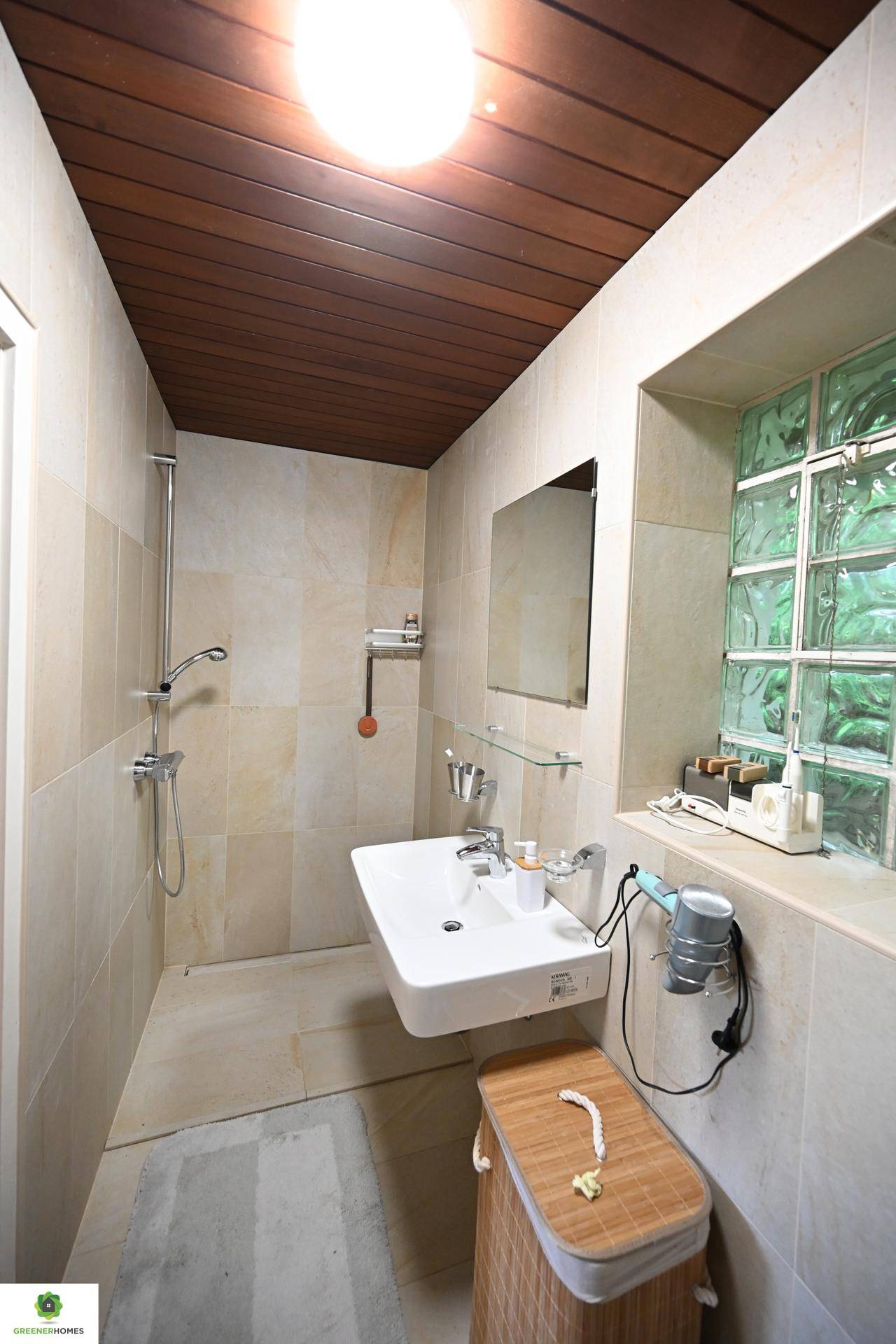 Kleines Badezimmer mit Dusche, Waschtisch und Glasbausteinen für natürliches Licht.