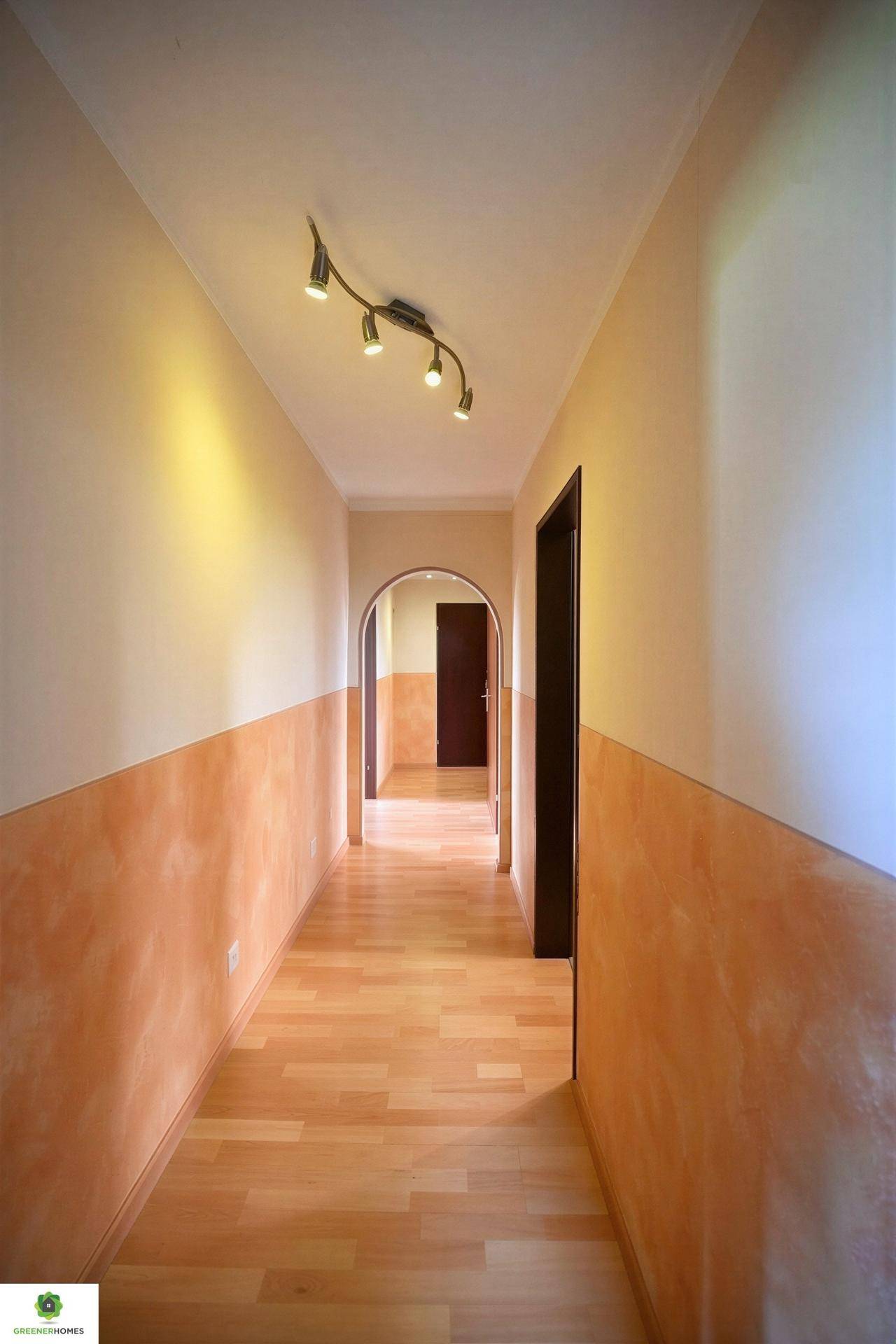 Heller Flur mit Holzboden und warmen Wandfarben, der zu weiteren Räumen führt.