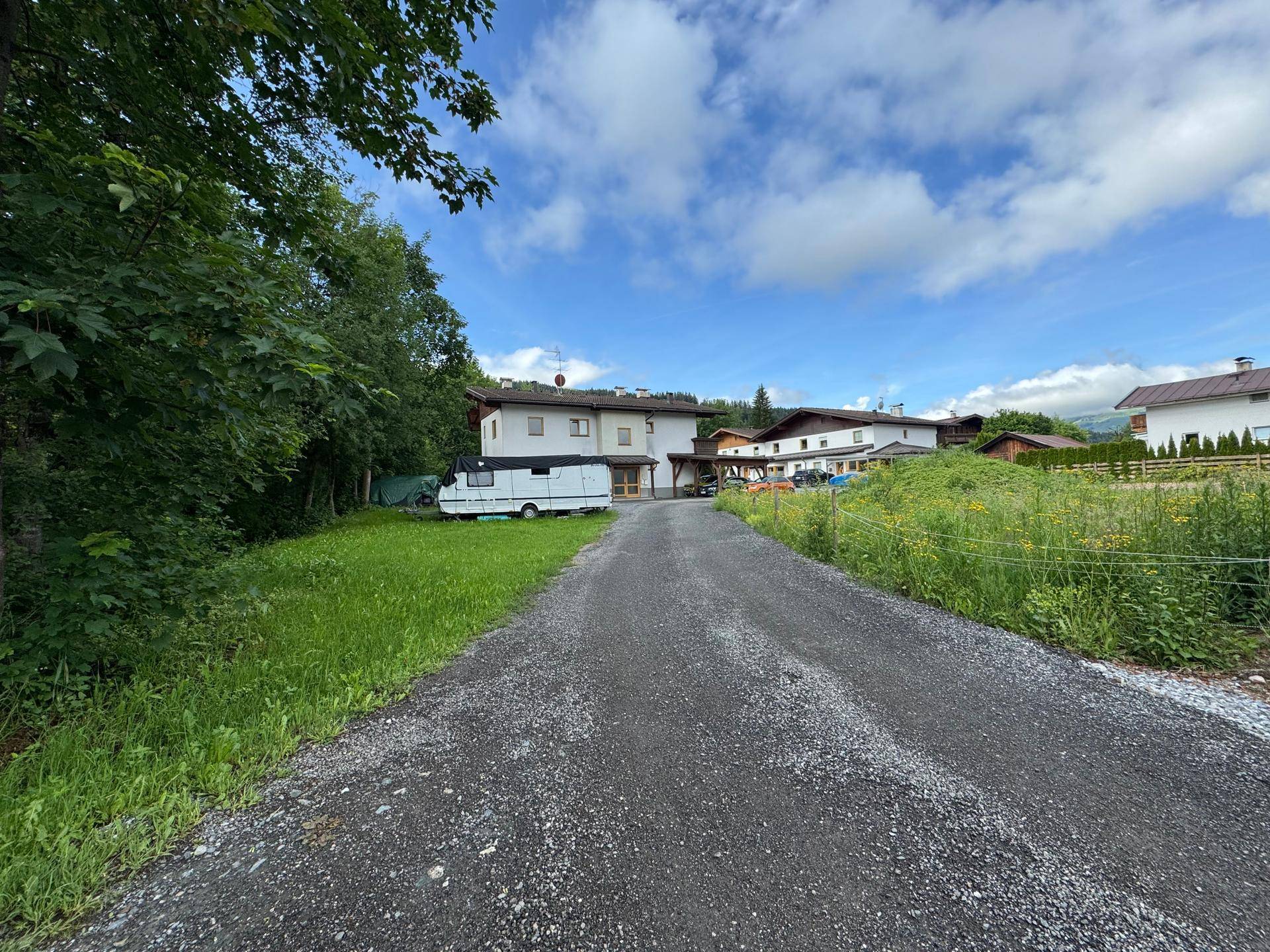 Weitläufige Außenansicht des Hauses mit Schotterzufahrt, umgeben von Natur und Bergblick.