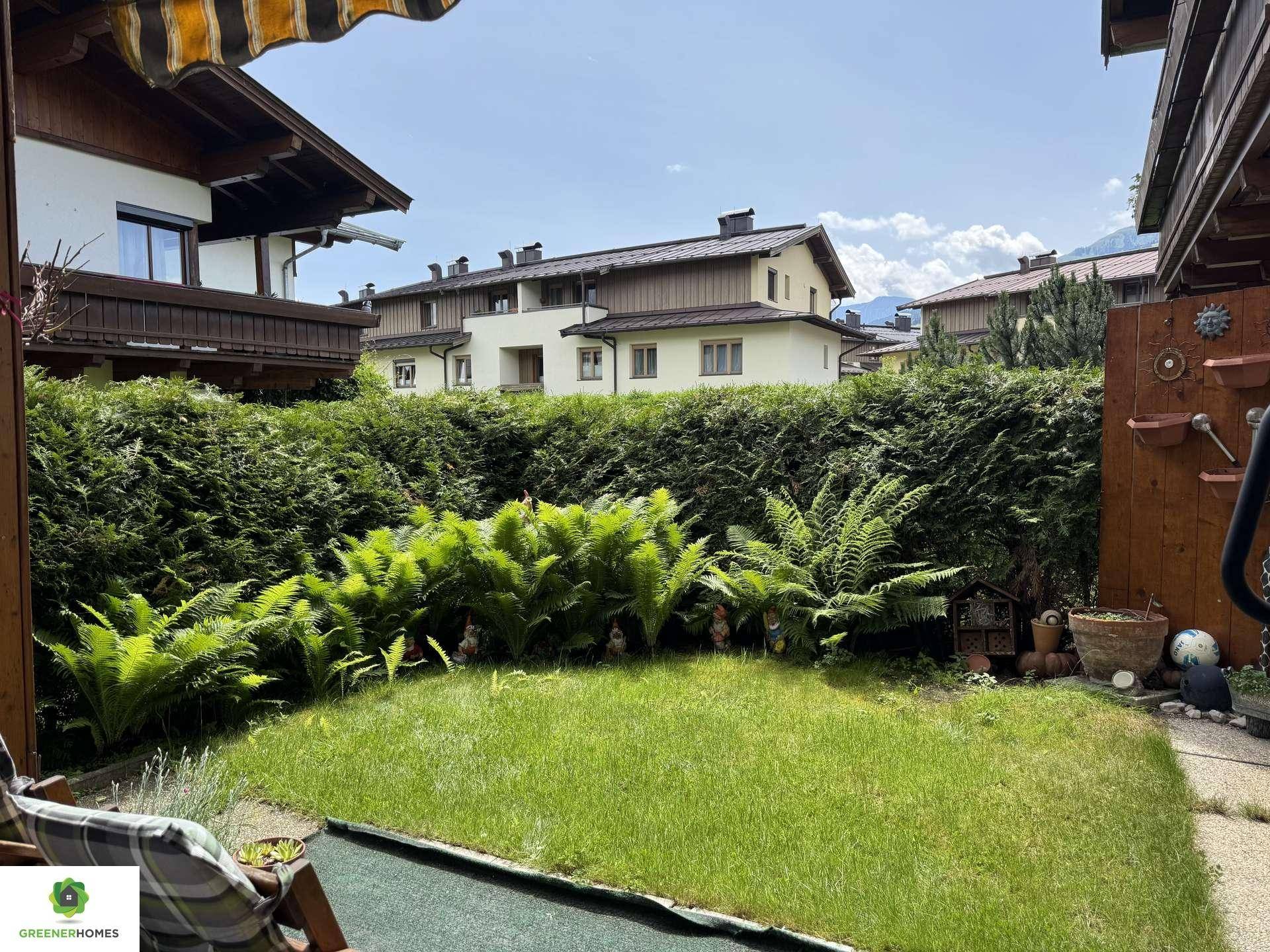 Kleiner, gepflegter Gartenbereich mit Rasen, hohen Hecken und Farnen.