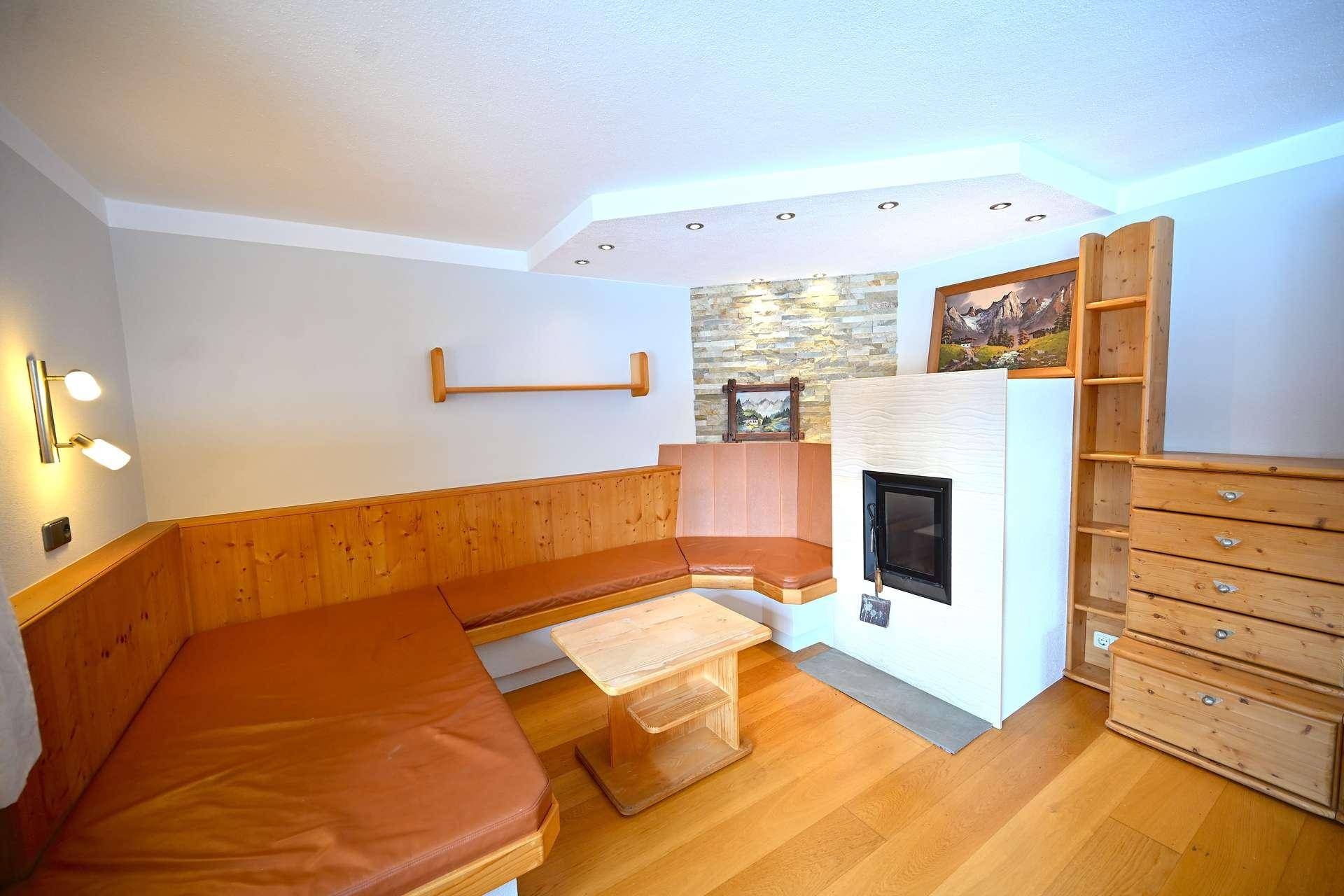 Gemütlicher Wohnbereich mit Holzbänken, Kamin und rustikaler Steinwand, ideal zum Entspannen.