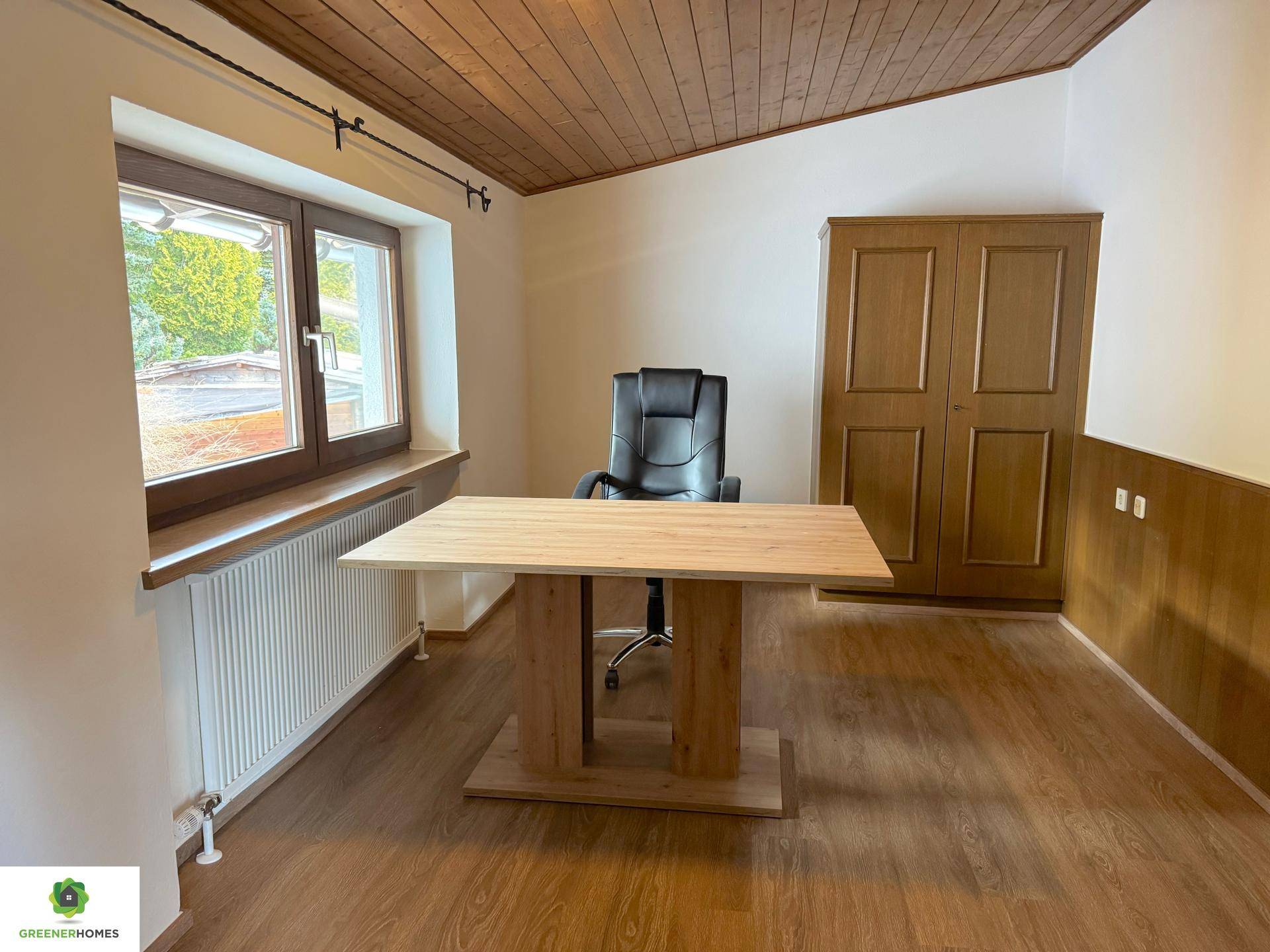 Funktionales Büro mit Holzbalkendecke, Laminatboden, Schreibtisch und integriertem Kleiderschrank.