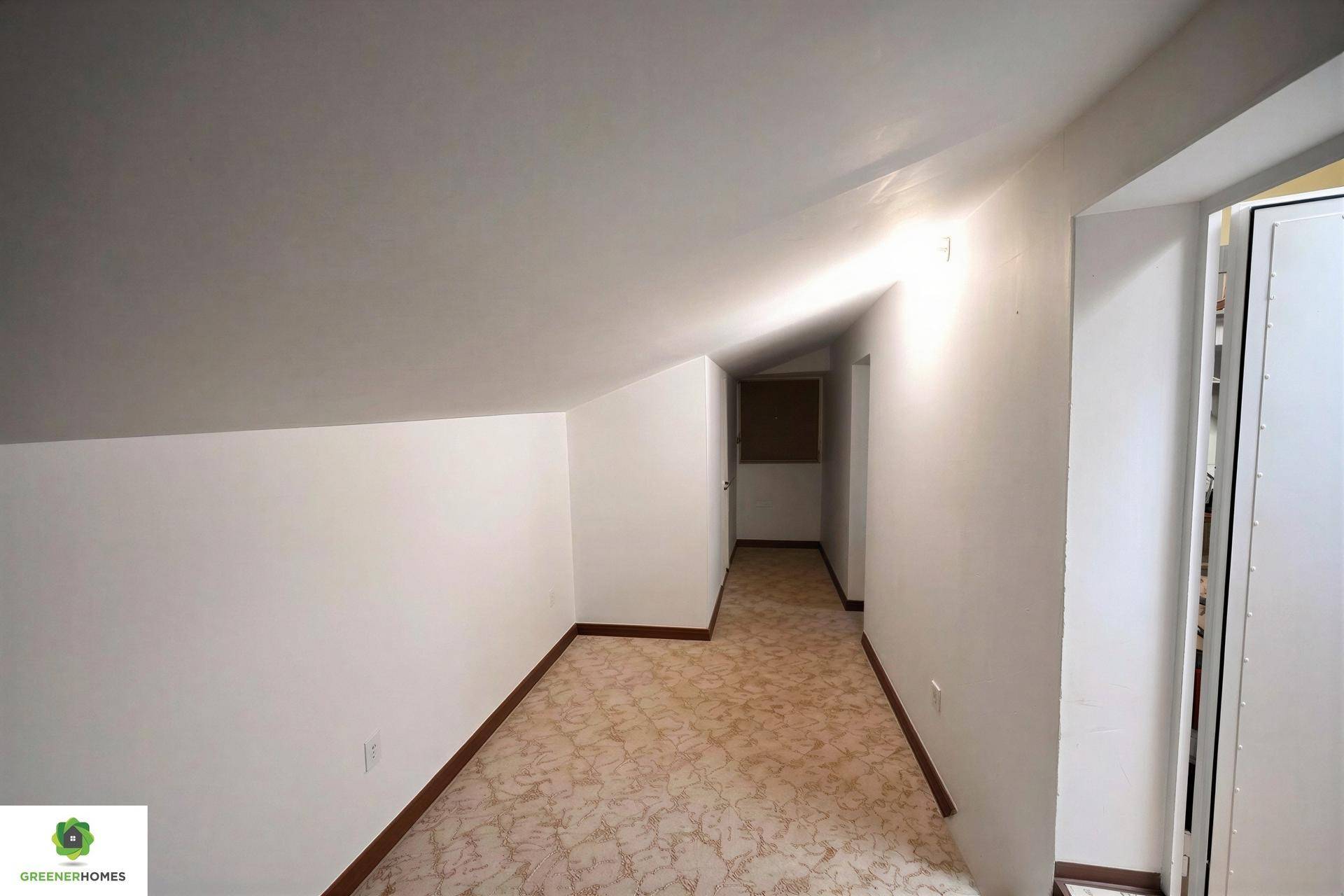 Schmaler Flur im Dachgeschoss mit Dachschräge und Teppichboden.