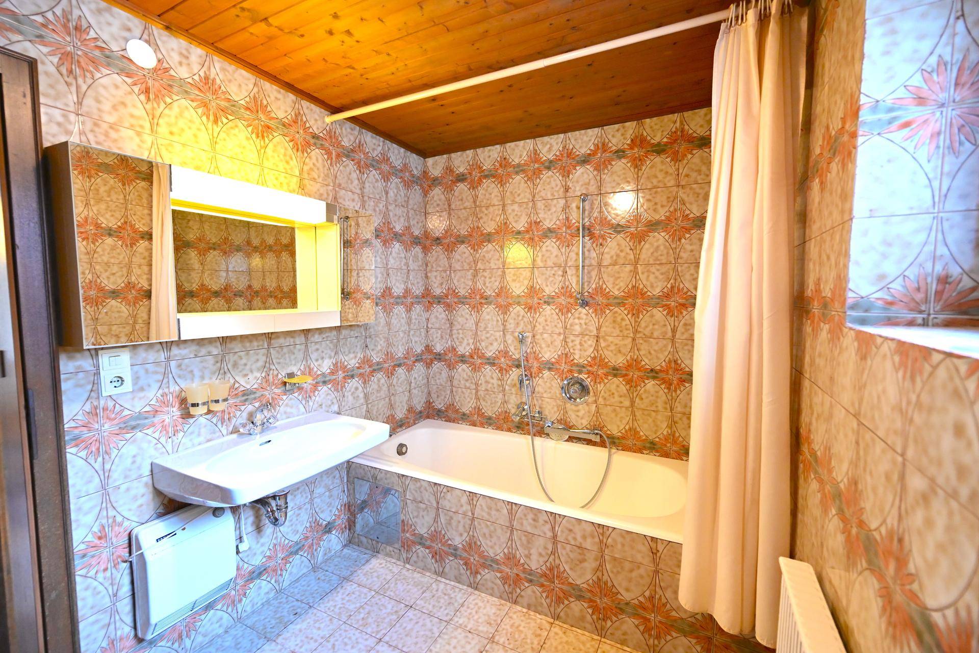 Badezimmer mit Badewanne, Waschbecken und gemusterten Fliesen im traditionellen Stil.