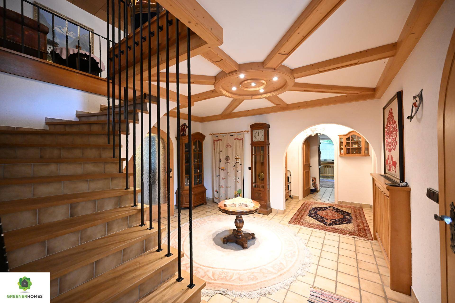 Repräsentativer Eingangsbereich mit Holztreppe, dekorativer Holzdecke und traditionellen Möbeln.