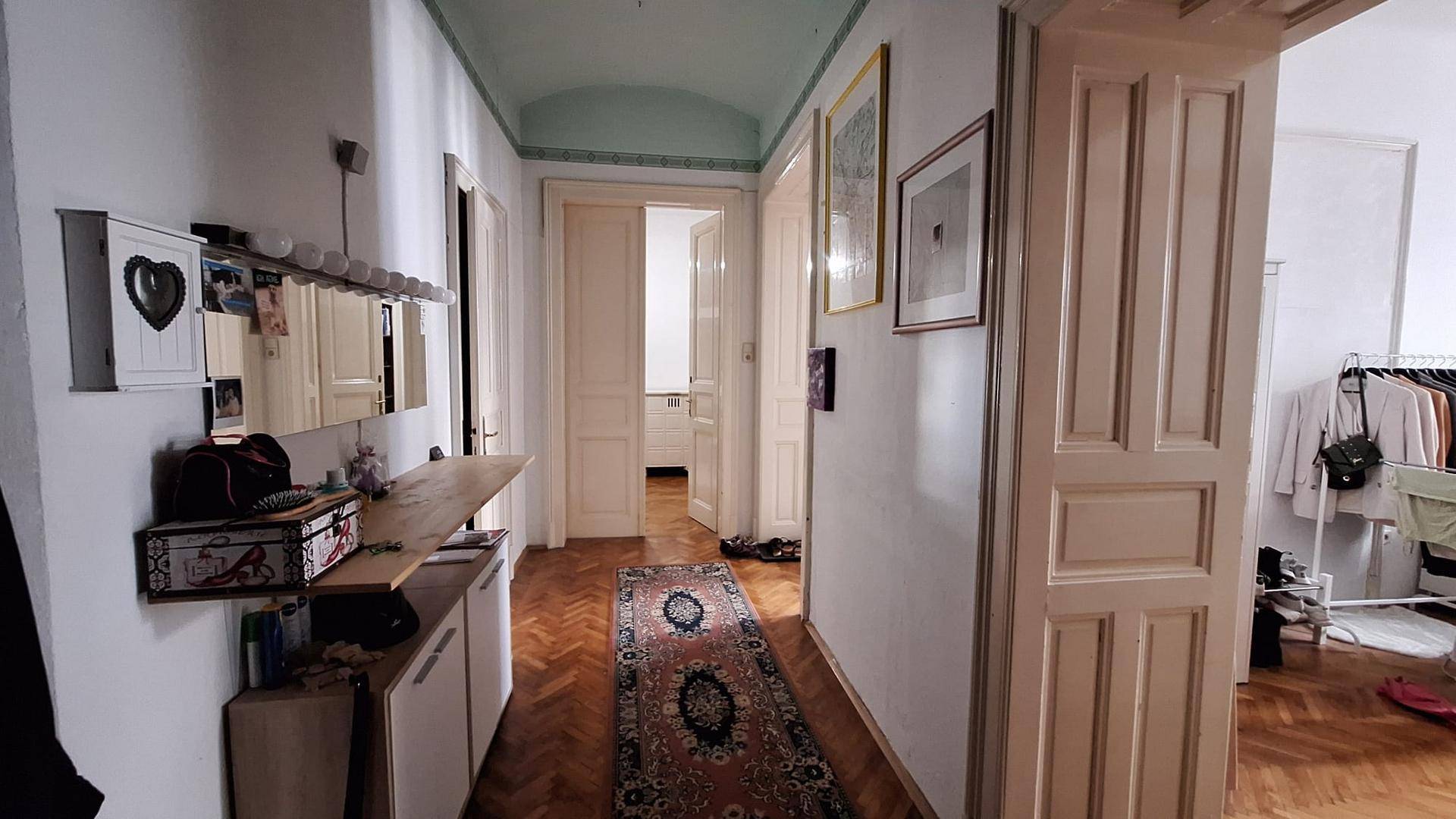 Langer Flur mit Fischgrätparkett, weißen Türen und einer mintgrünen Decke in einem Altbau.