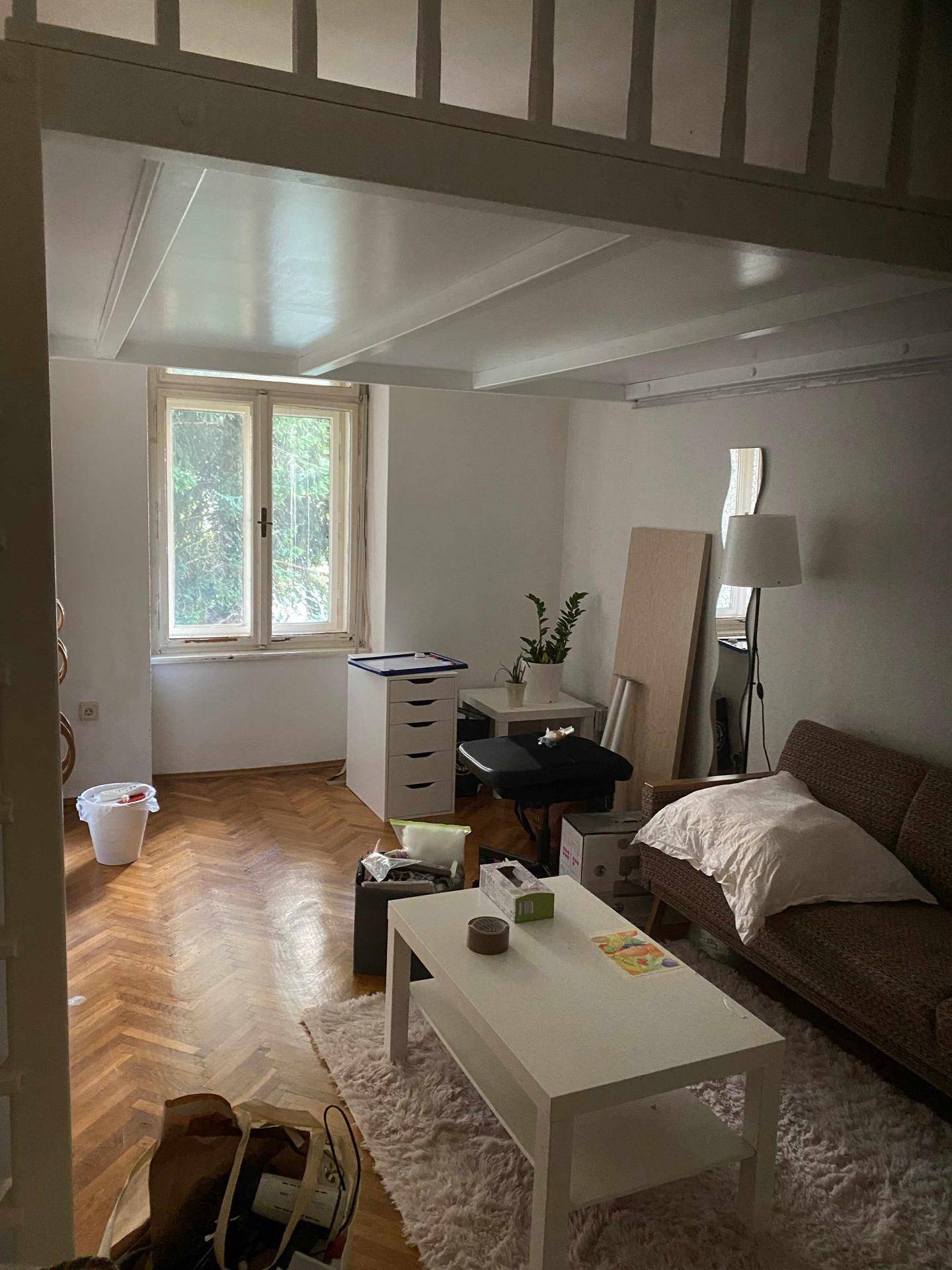 Gemütliches Wohnzimmer mit Fischgrätparkett, Sofa, Couchtisch und Blick ins Grüne.