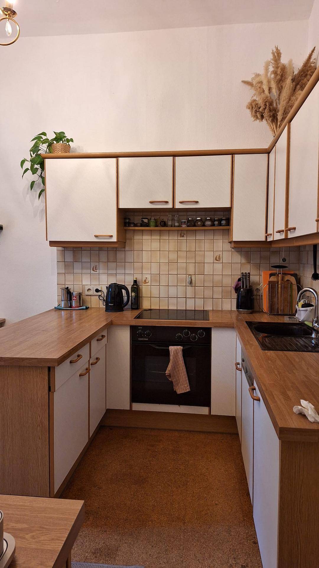 U-förmige Küche mit Holz-Arbeitsplatten, weißen Schränken, Backofen und Induktionskochfeld.