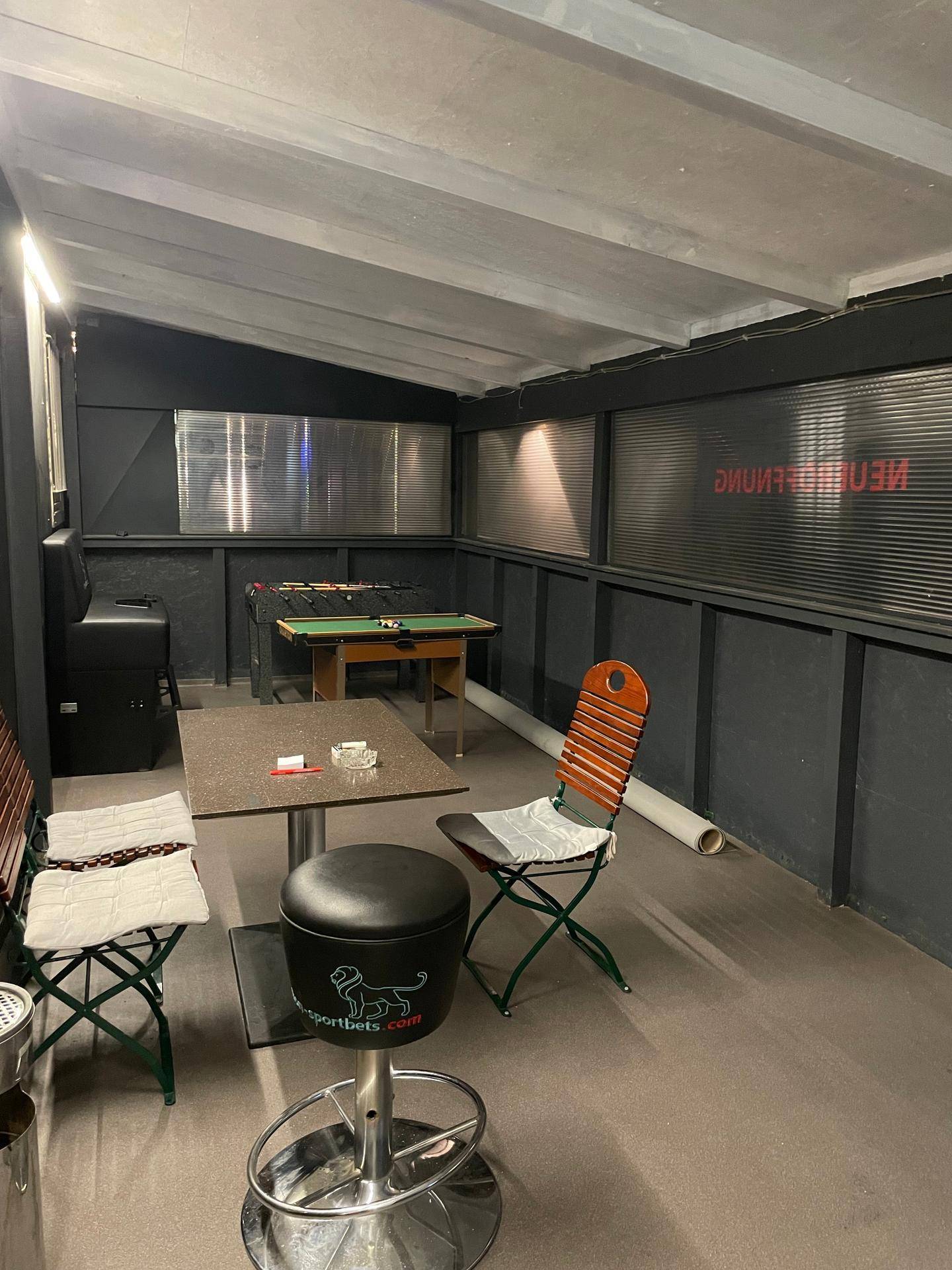 Überdachter Spielbereich mit Tischfußball, Stehtischen und Sitzgelegenheiten.