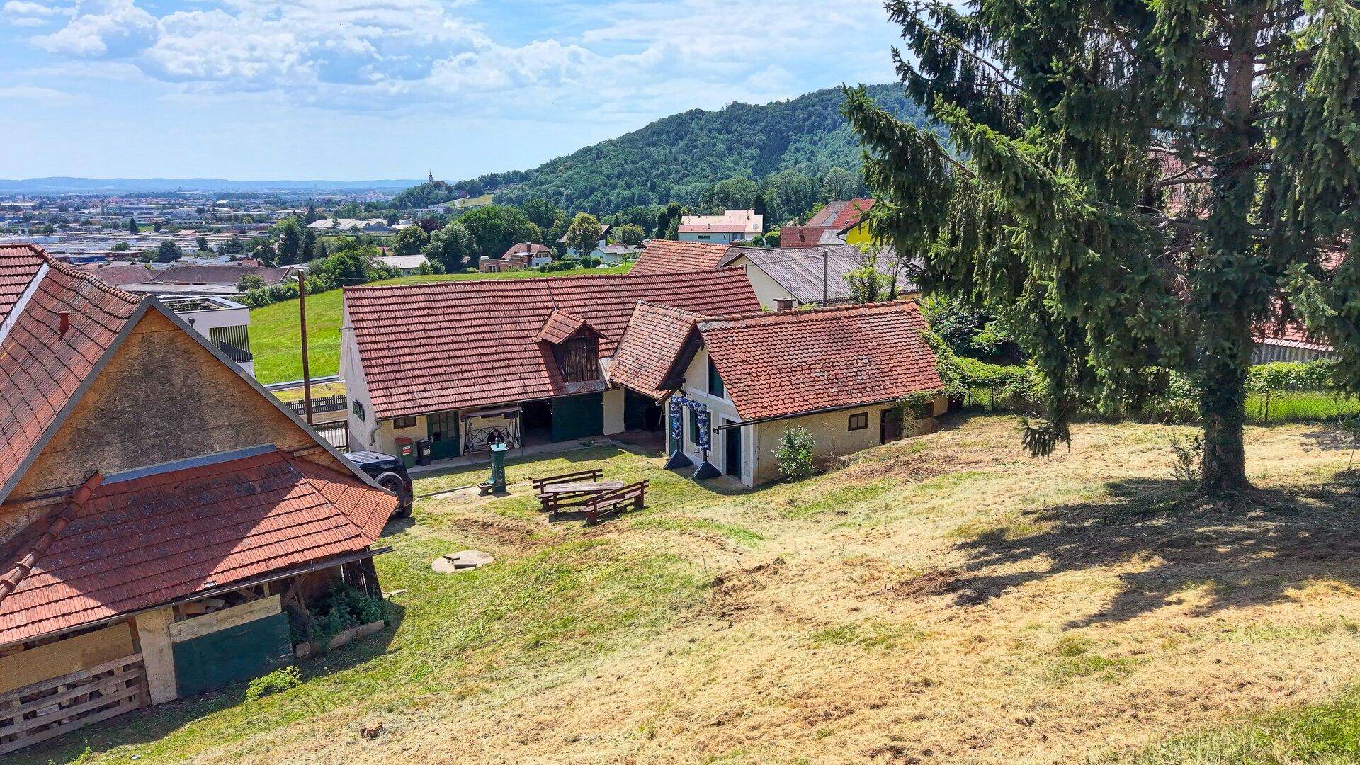 Ansicht des Anwesens mit mehreren Gebäuden, rotem Ziegeldach und ländlicher Umgebung.
