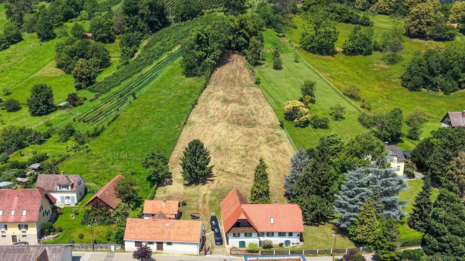 Weitläufige Luftaufnahme des Anwesens mit Weinbergen, Feldern und Wohngebäuden in hügeliger Landschaft.