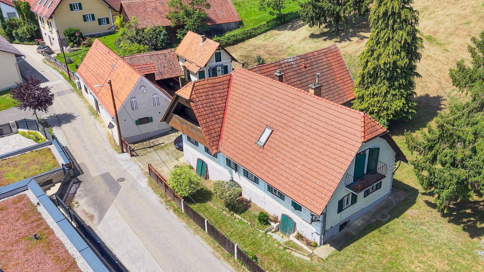 Luftaufnahme des Hauptgebäudes mit rotem Ziegeldach und angrenzendem modernen Neubau.