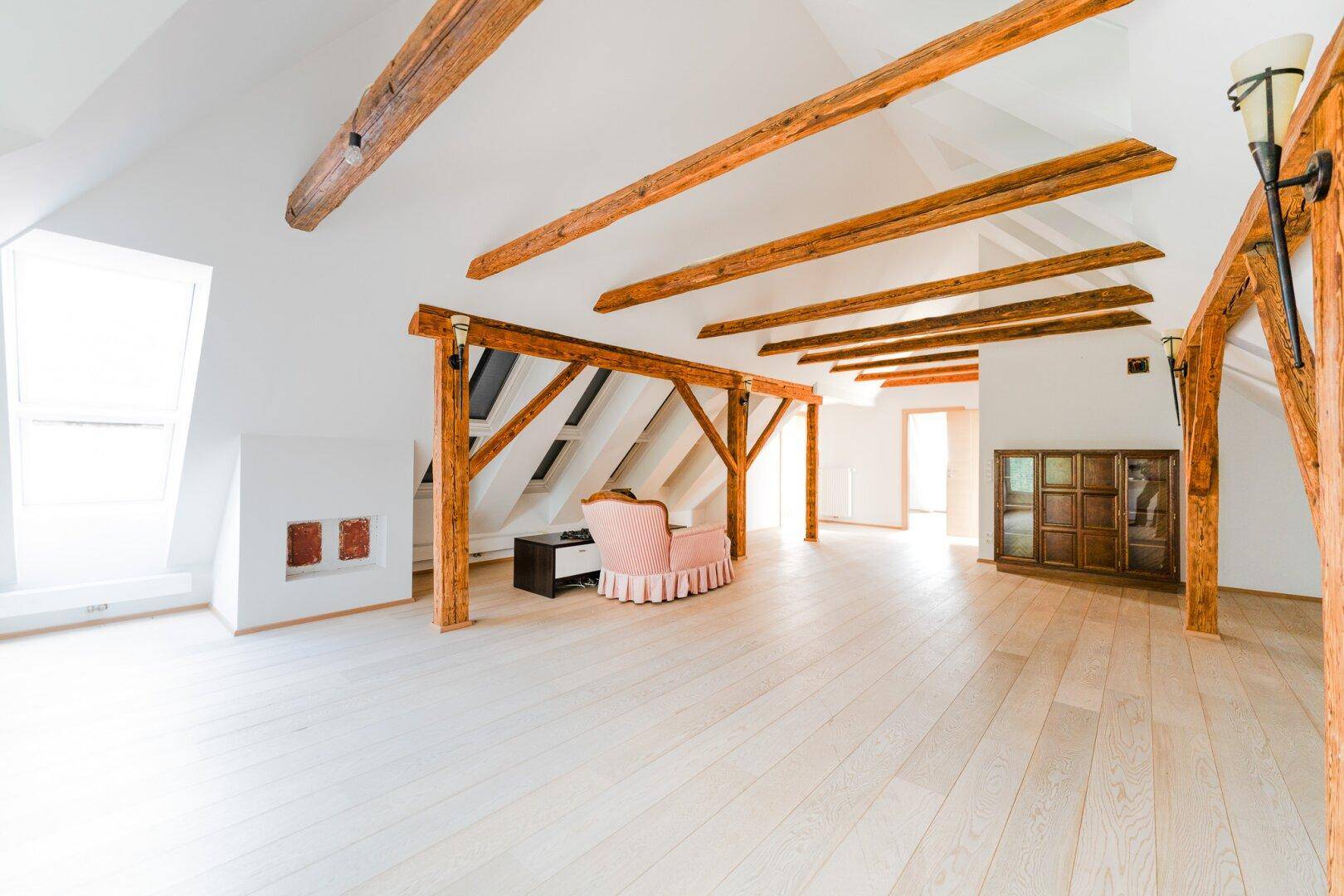 Heller Dachbodenraum mit freiliegenden Holzbalken, Holzboden und viel Platz für individuelle Nutzung.