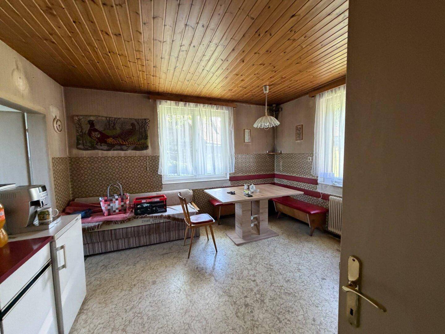 Gemütliche Wohnküche mit Holztäfelung an der Decke und einer Eckbank.