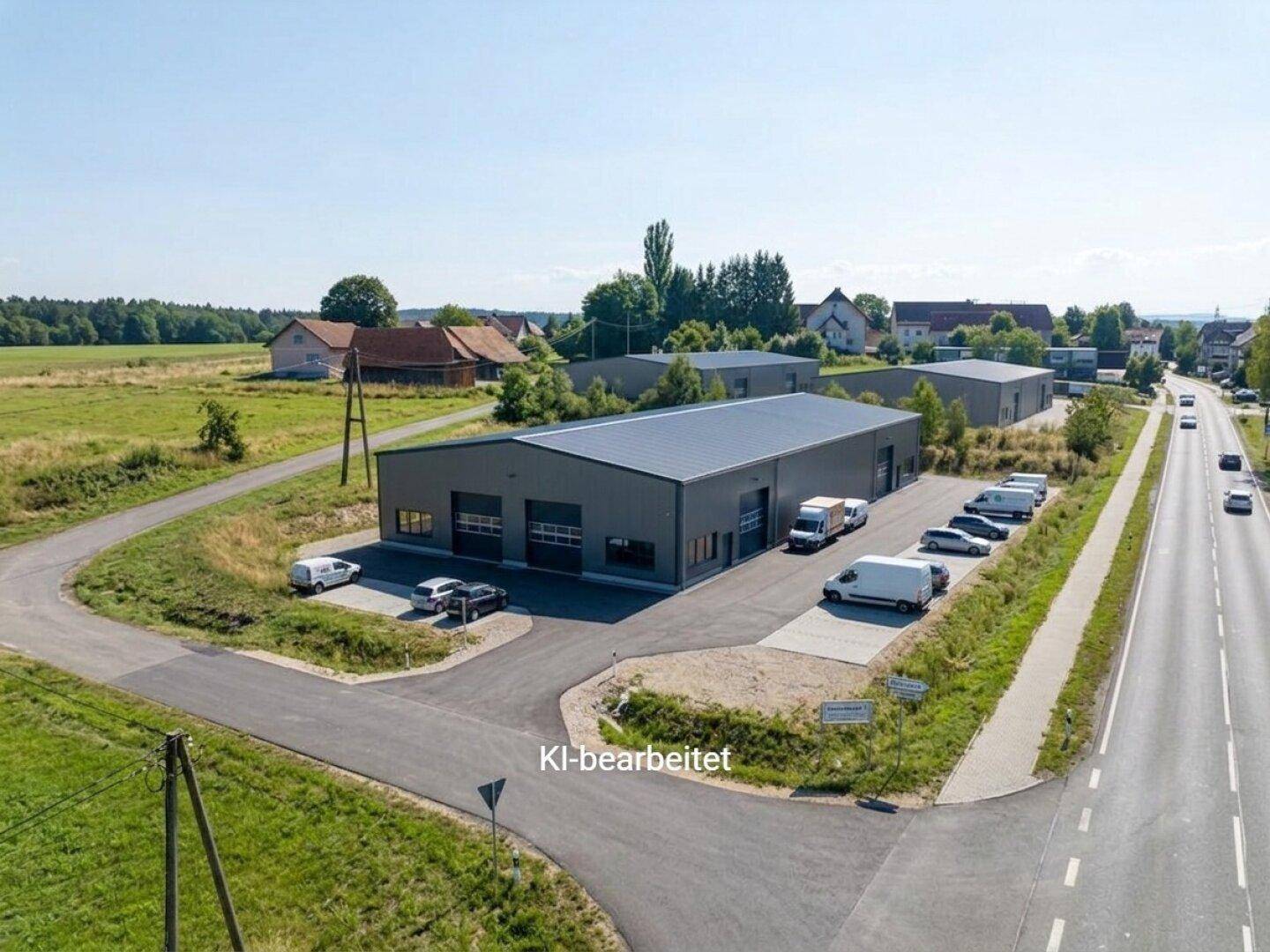 Luftaufnahme eines modernen Gewerbegebäudes mit Parkplätzen, umgeben von Feldern und einer Straße.