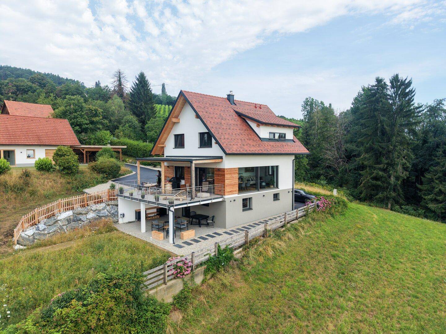 Neubau mit moderner Architektur, großer Terrasse und weitem Blick über die hügelige Landschaft.