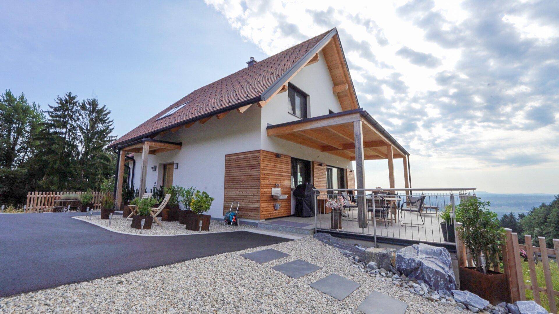 Modernes Einfamilienhaus mit überdachter Terrasse und weitem Blick über die Landschaft.