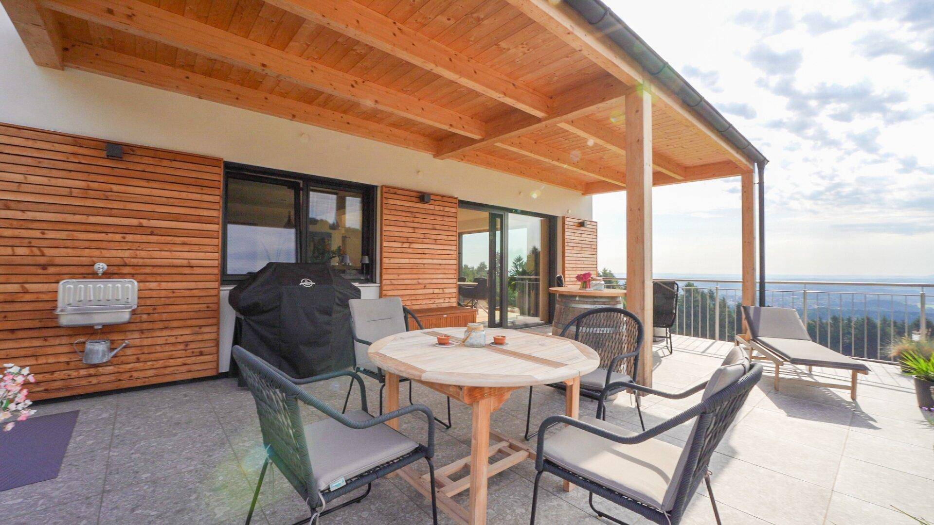 Geräumige Terrasse mit Holzdach, Grillplatz und Sitzgelegenheiten für gesellige Stunden.