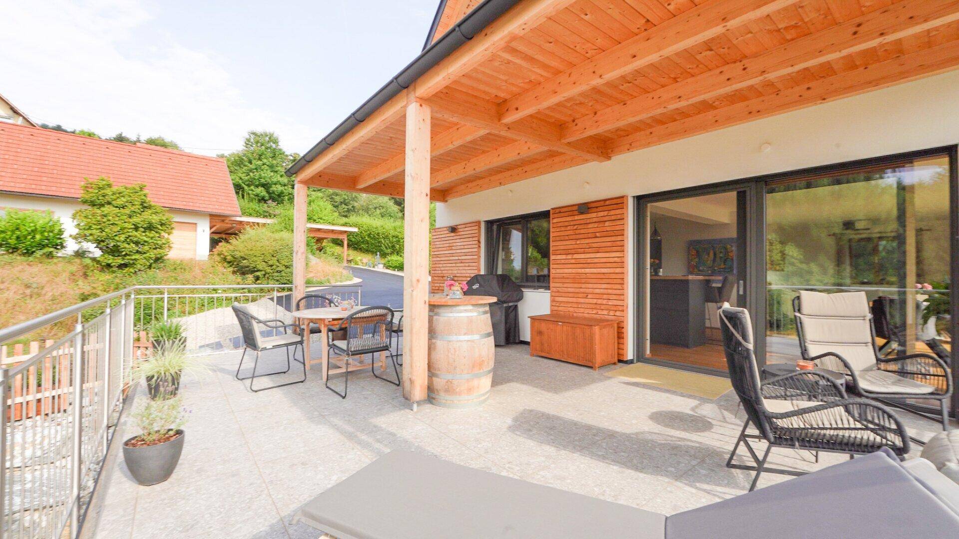 Große überdachte Terrasse mit Essbereich und Liegestühlen, ideal zum Entspannen im Freien.