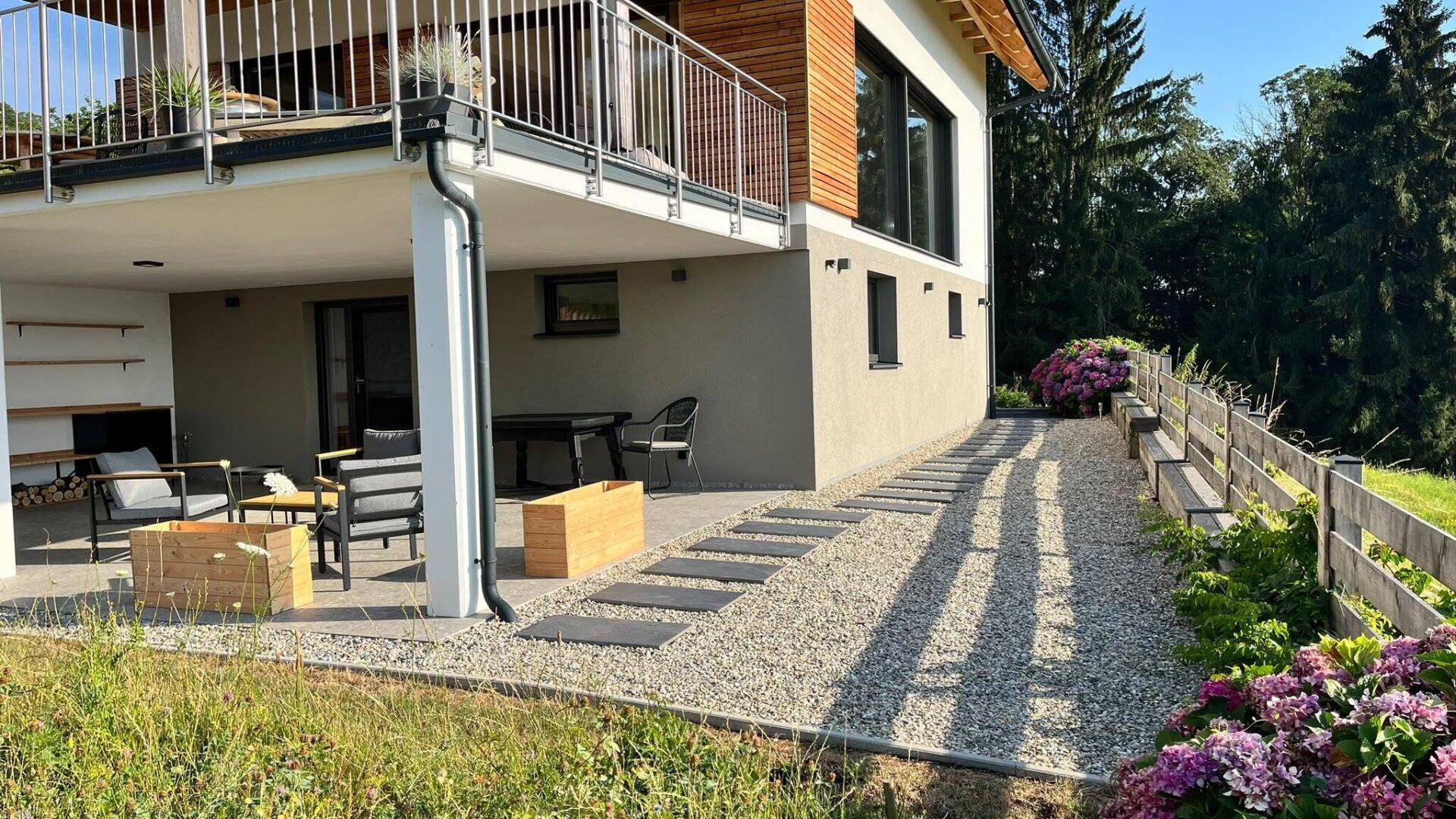 Ansicht des Hauses von der Seite mit Terrasse, Gartenweg und gepflegter Bepflanzung.