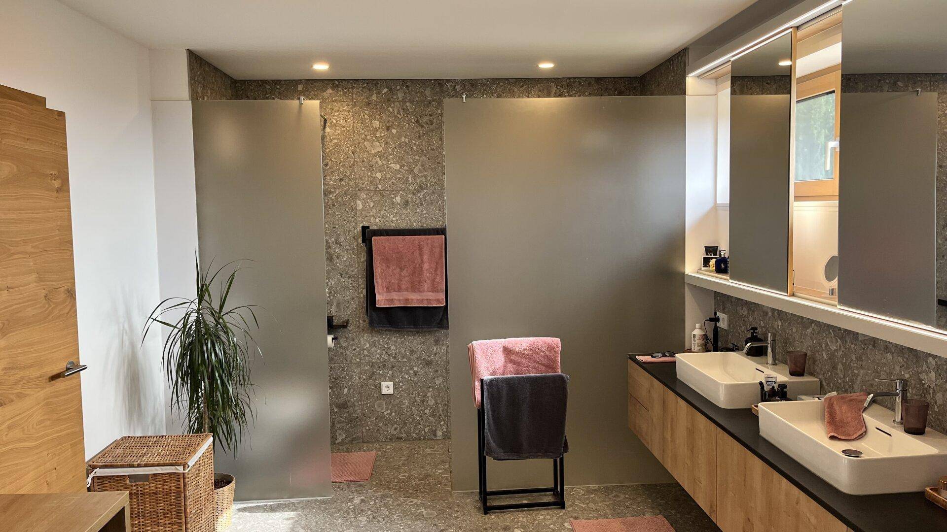 Modernes Badezimmer mit Doppelwaschbecken, begehbarer Dusche und großformatigen Fliesen.