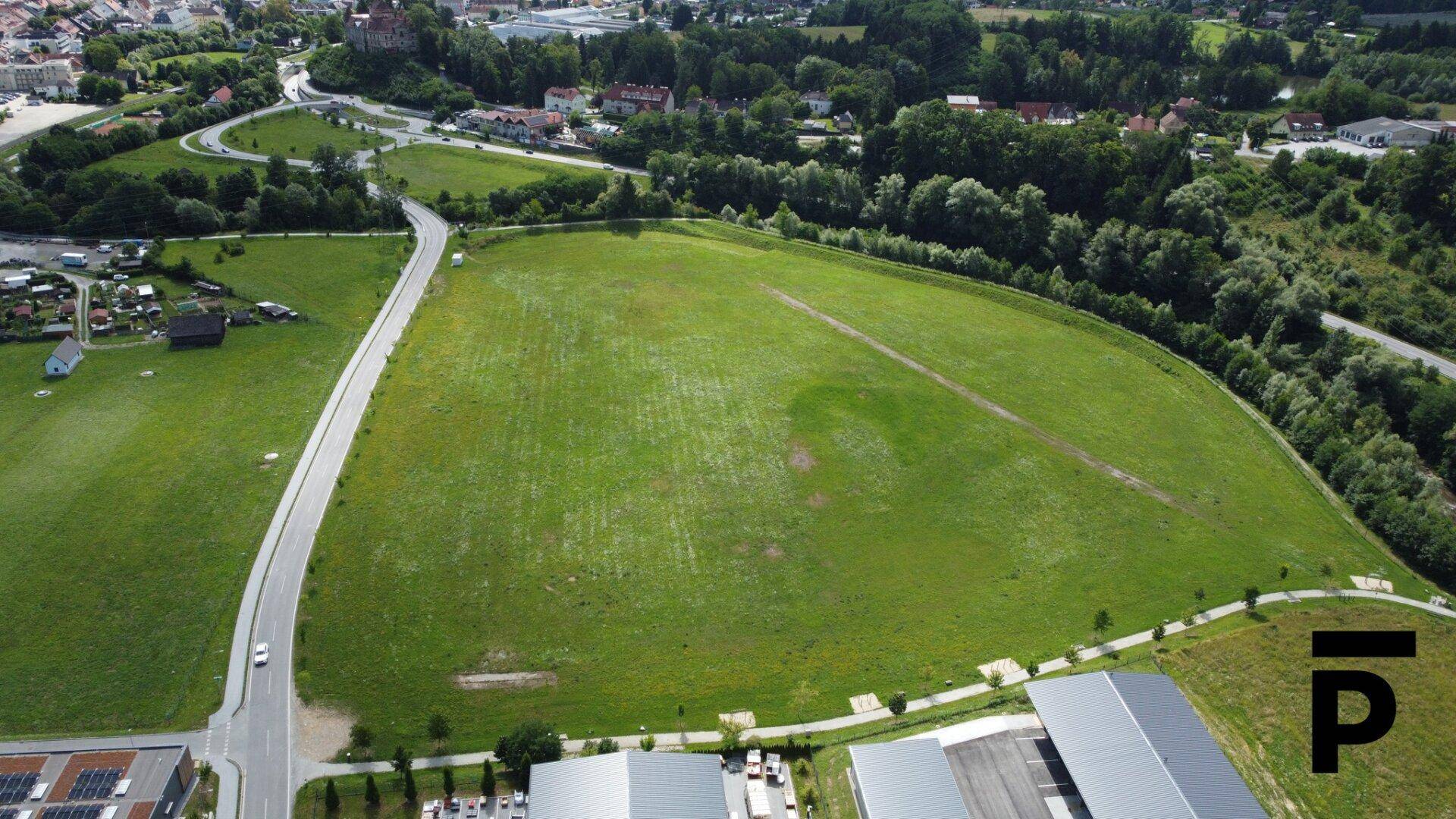 Weitläufiges grünes Grundstück aus der Vogelperspektive mit angrenzenden Straßen und Gebäuden.
