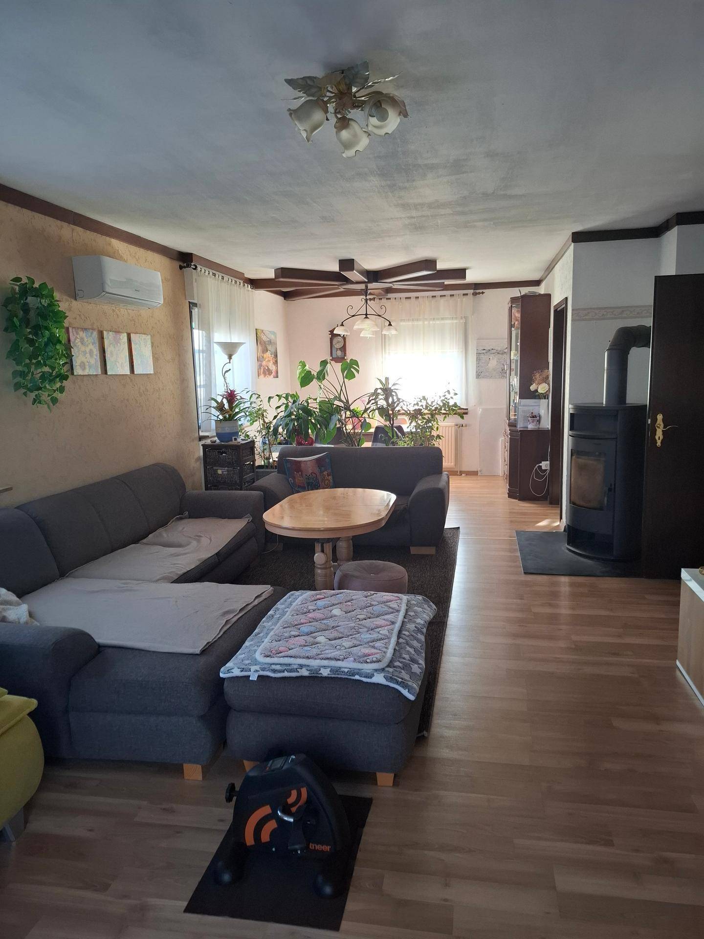 Geräumiges Wohnzimmer mit Kaminofen, Klimaanlage und bequemer Sofalandschaft.