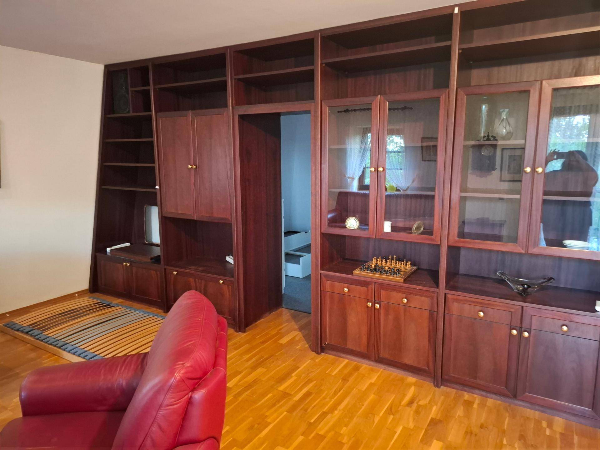 Wohnzimmer mit großer, dunkler Holzschrankwand und hellem Parkettboden.