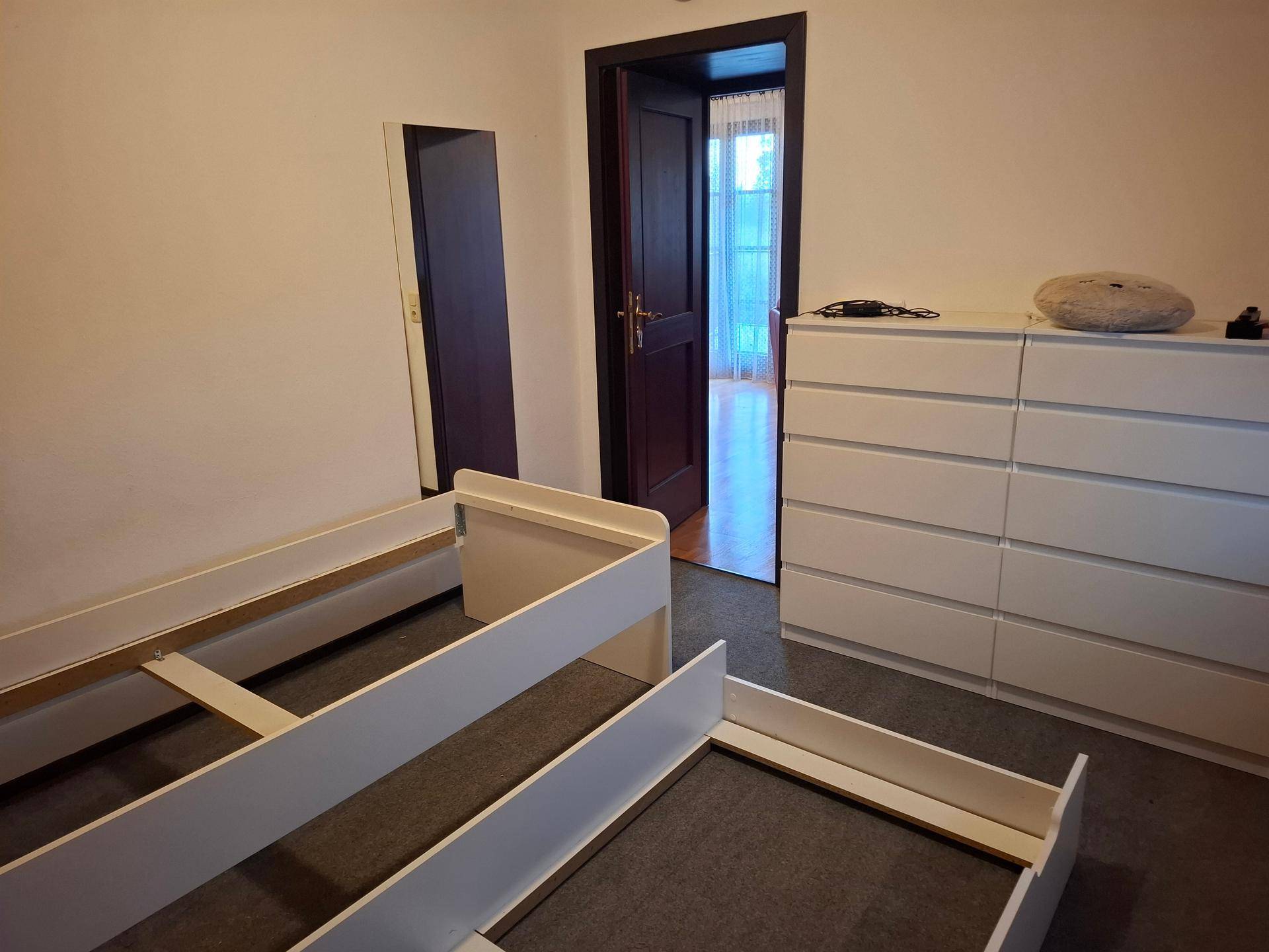 Schlafzimmer mit weißer Kommode und zwei Bettgestellen, bereit zur Einrichtung.