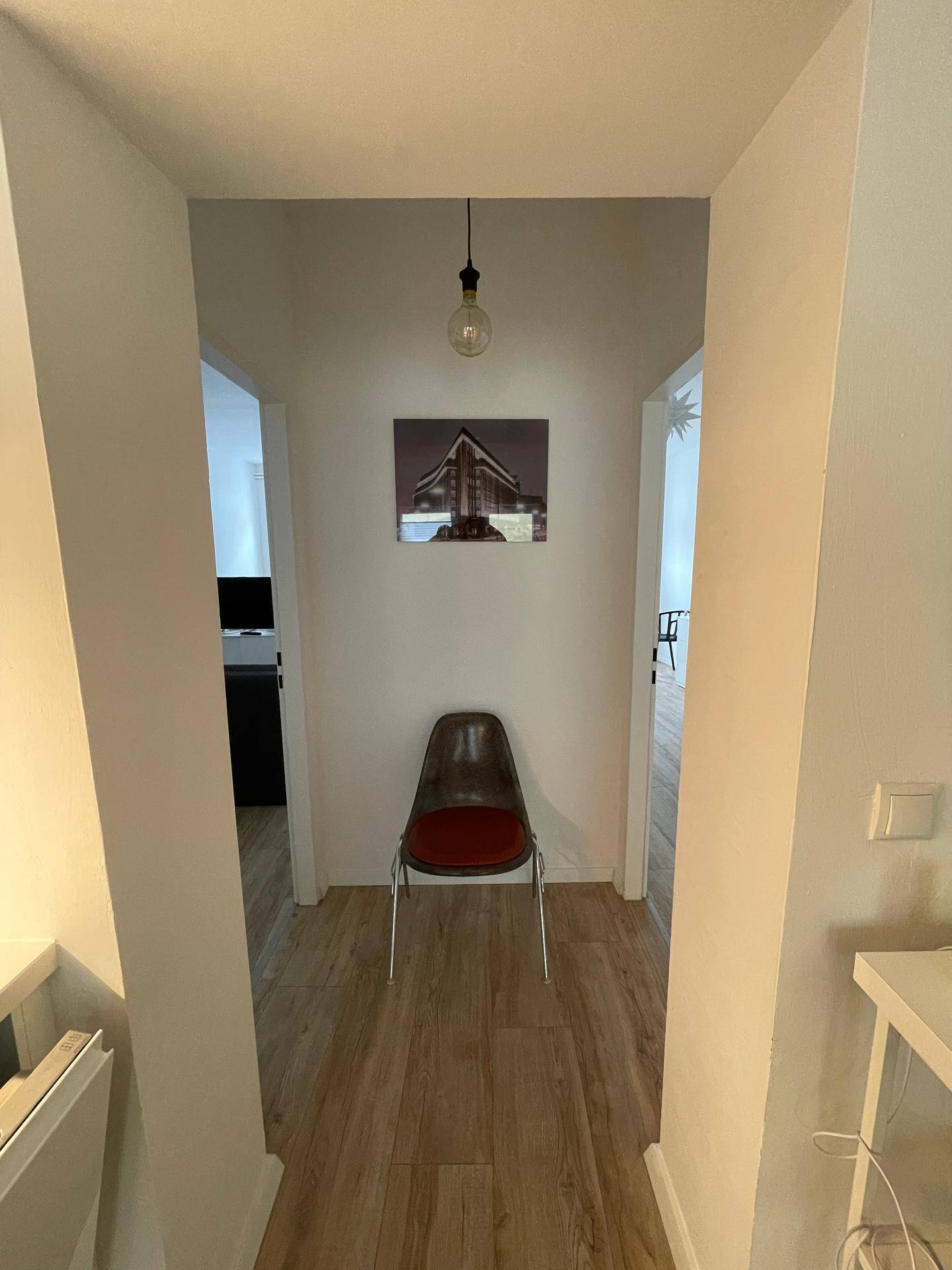 Heller Flur mit Holzfußboden und einem einzelnen Stuhl als minimalistische Dekoration.