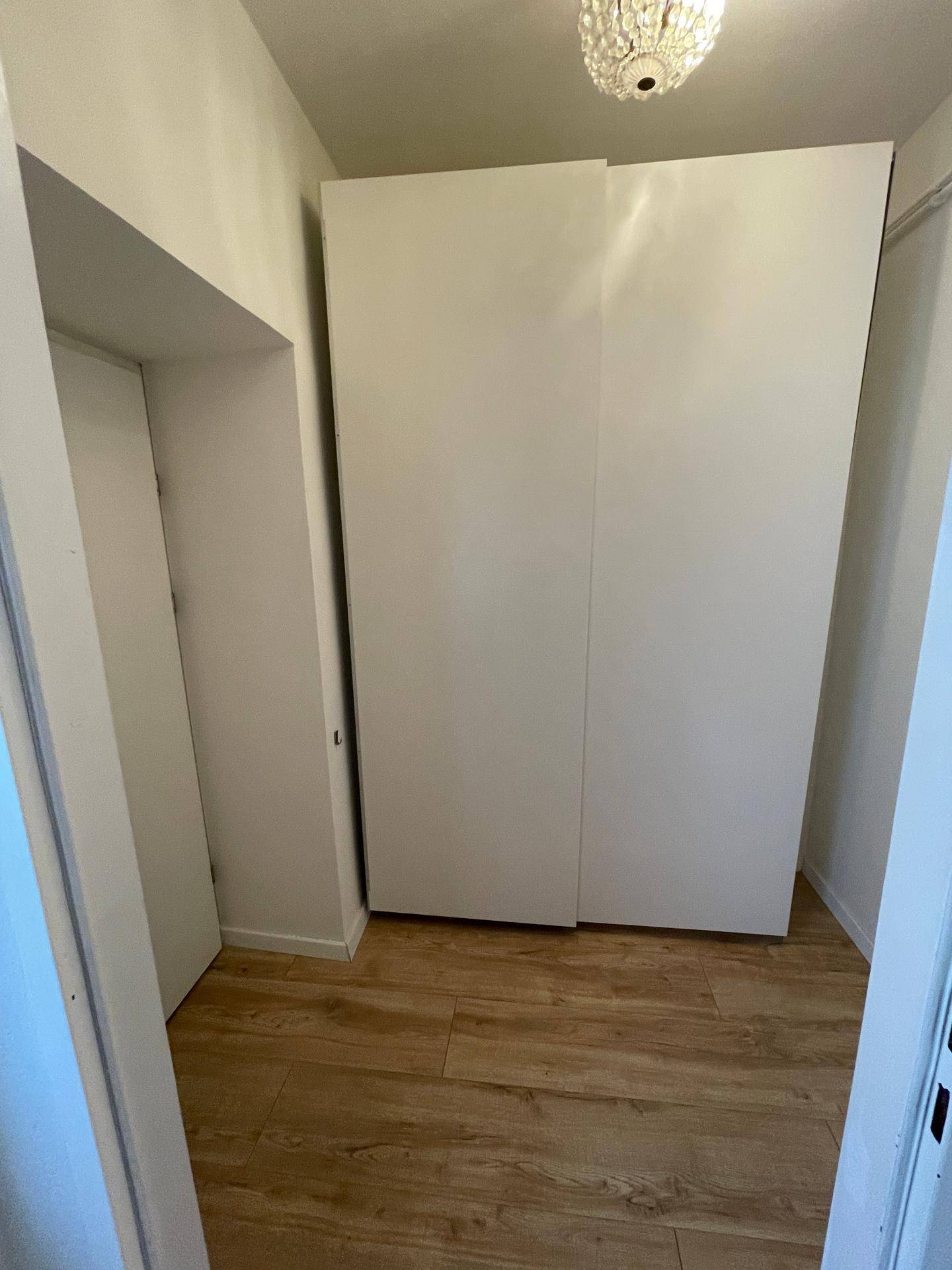 Heller Flurbereich mit großen weißen Schränken und durchgehendem Holzfußboden.
