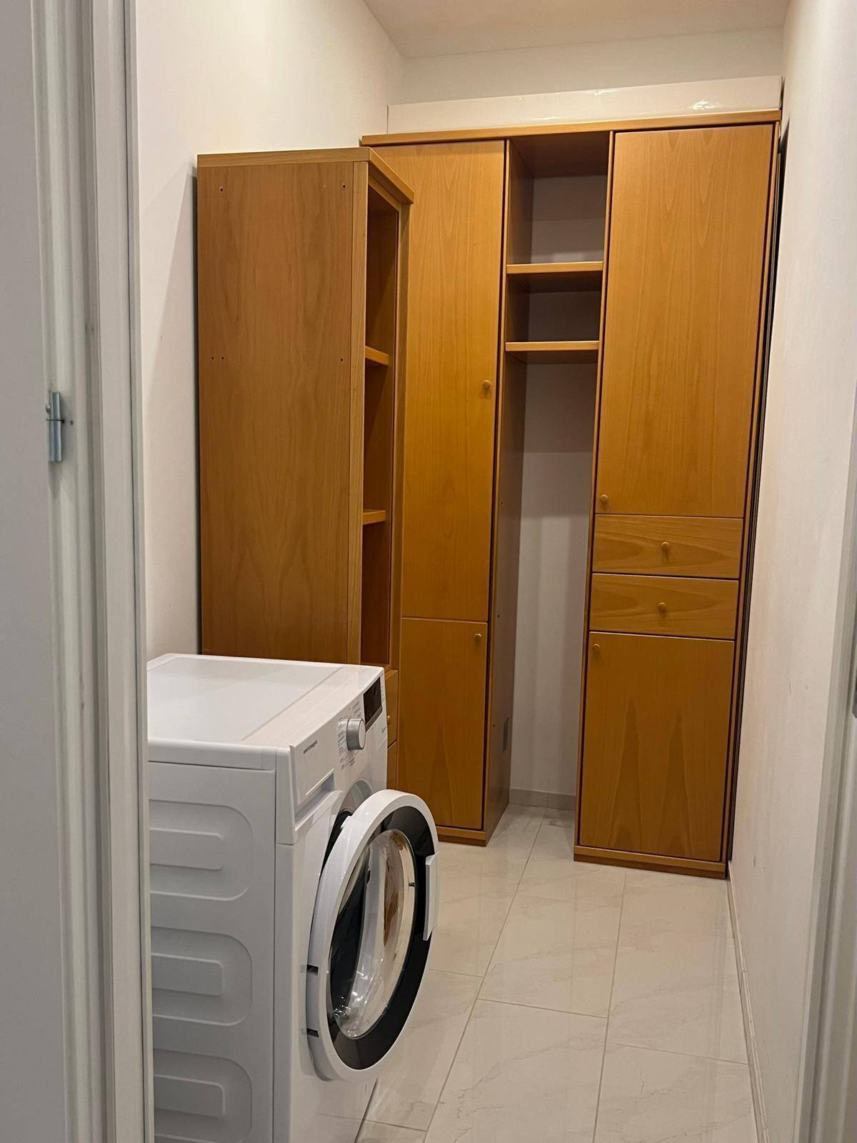 Praktischer Hauswirtschaftsraum mit Waschmaschine und integrierten Holzschränken.