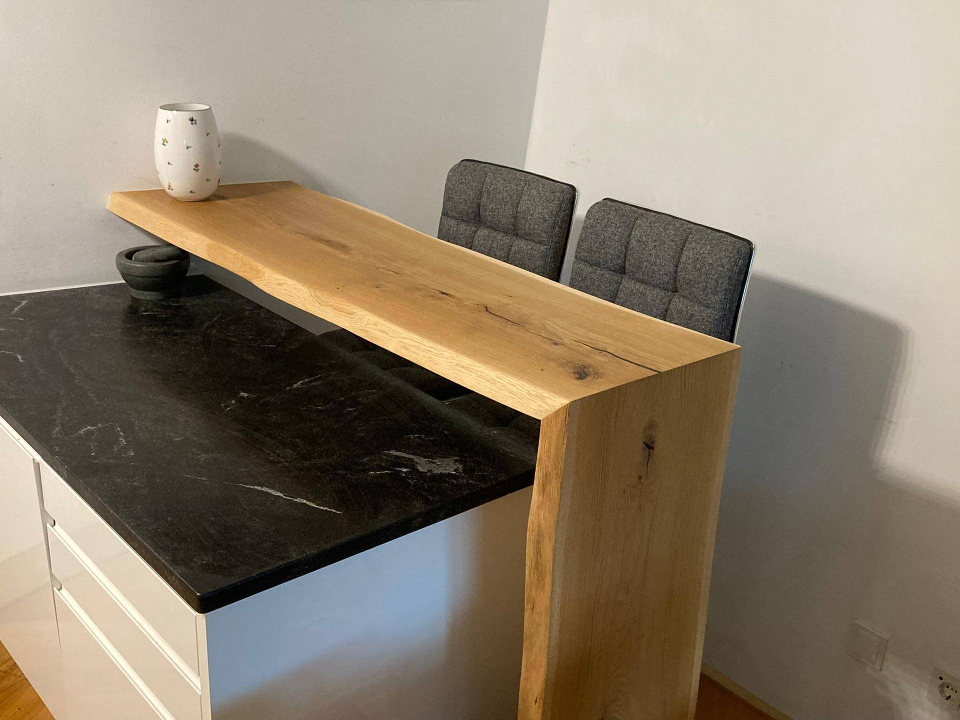 Detailansicht der eleganten Frühstücksbar aus Massivholz und der dunklen Granitarbeitsplatte.