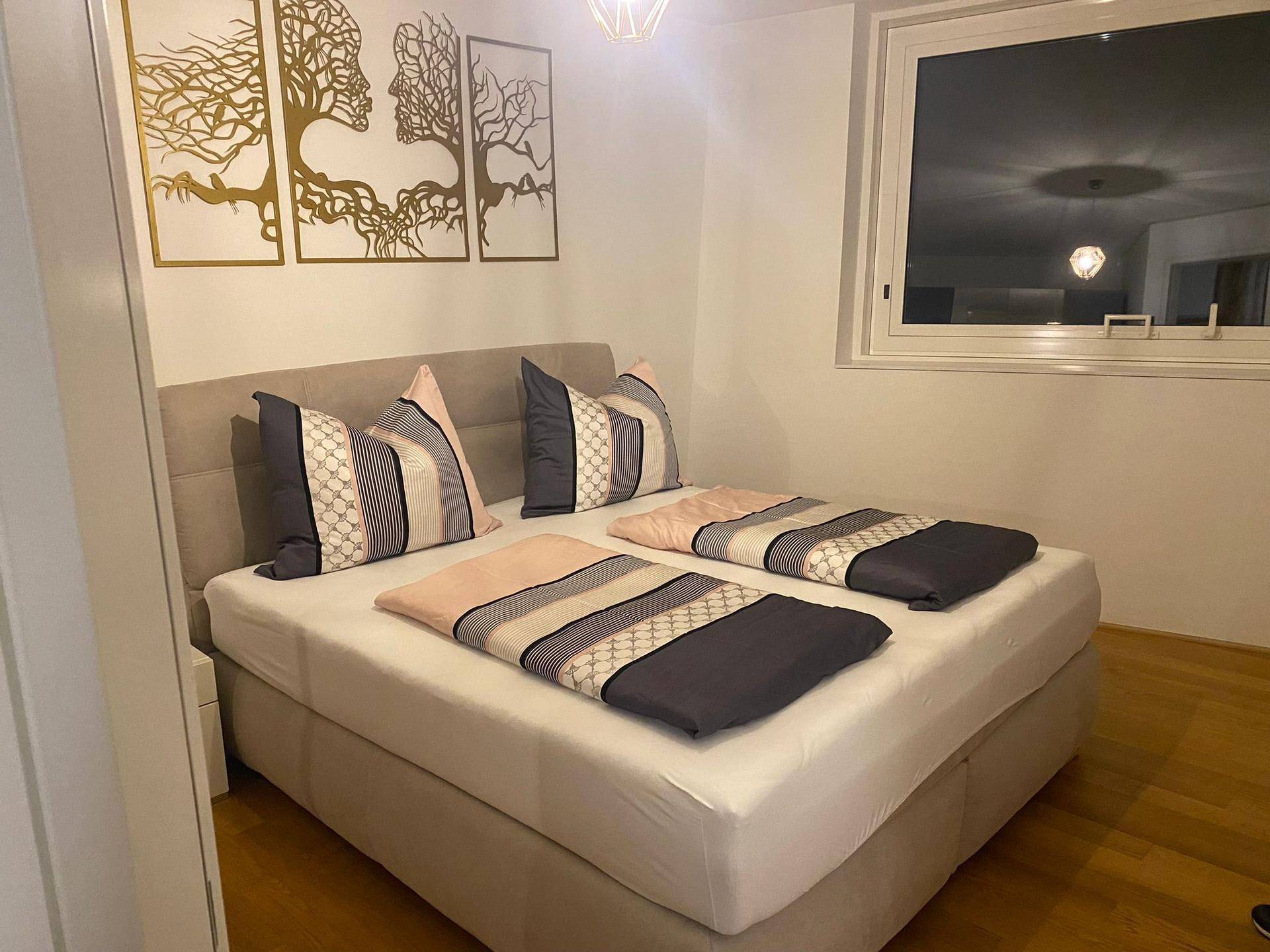 Gemütliches Schlafzimmer mit großem Boxspringbett, moderner Bettwäsche und dekorativer Wandkunst.