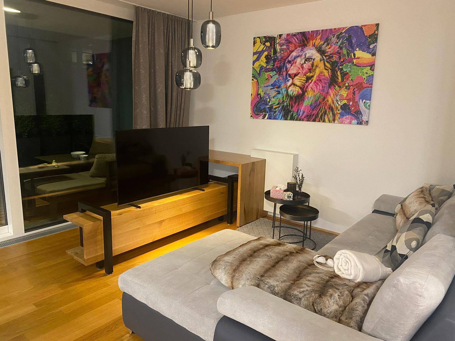 Modernes Wohnzimmer mit bequemer Couch, TV-Möbel und farbenfrohem Kunstwerk an der Wand.