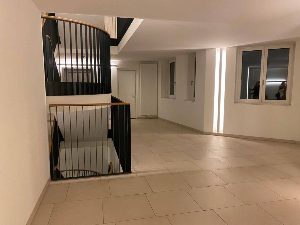 Geräumiger Flur mit moderner Wendeltreppe, Fliesenboden und indirekter Beleuchtung.