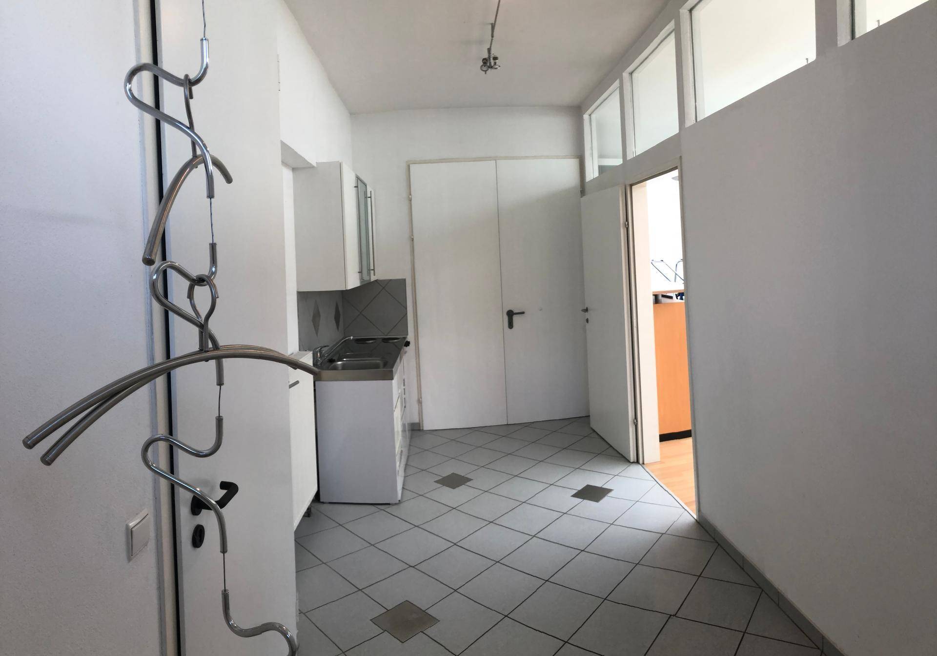 Heller Flur mit Fliesenboden, einer kleinen Küchenzeile und Zugang zu weiteren Räumen.