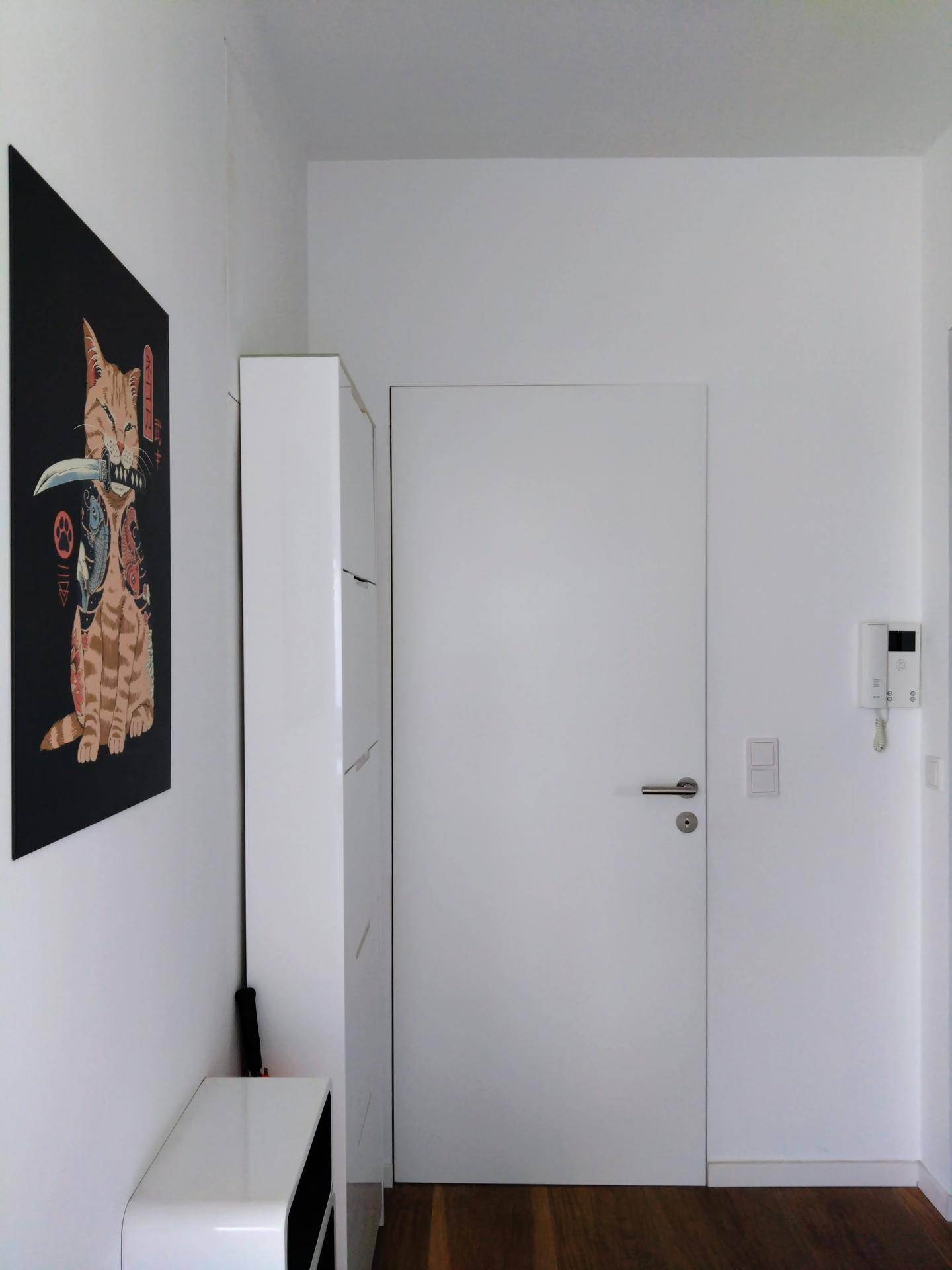 Heller Flur mit weißer Tür und modernem Kunstwerk an der Wand.