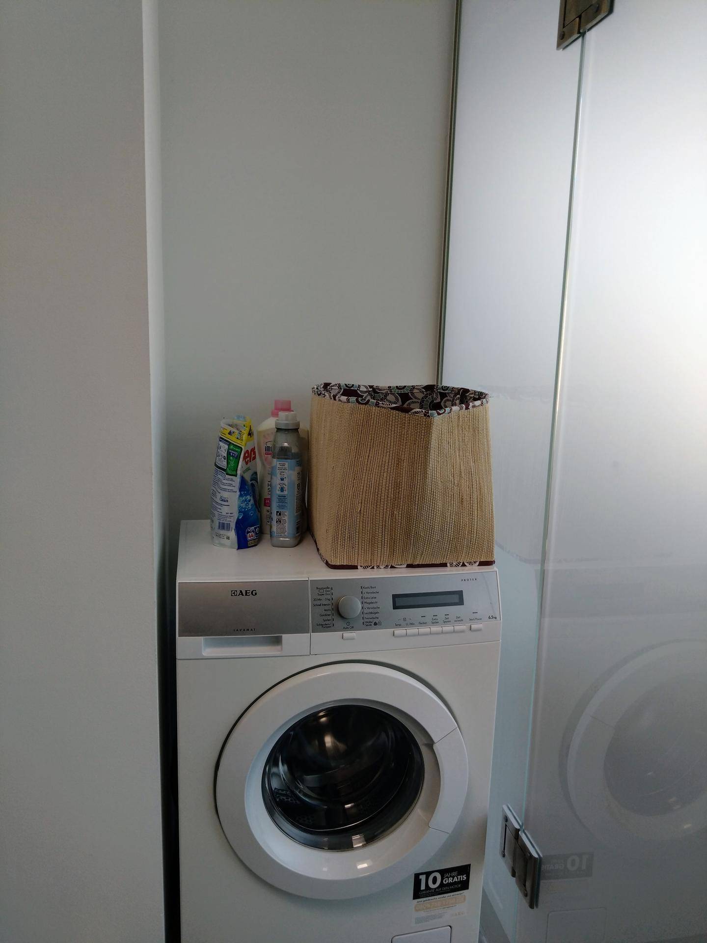 Waschmaschine in einem praktischen Hauswirtschaftsraum mit Stauraum.