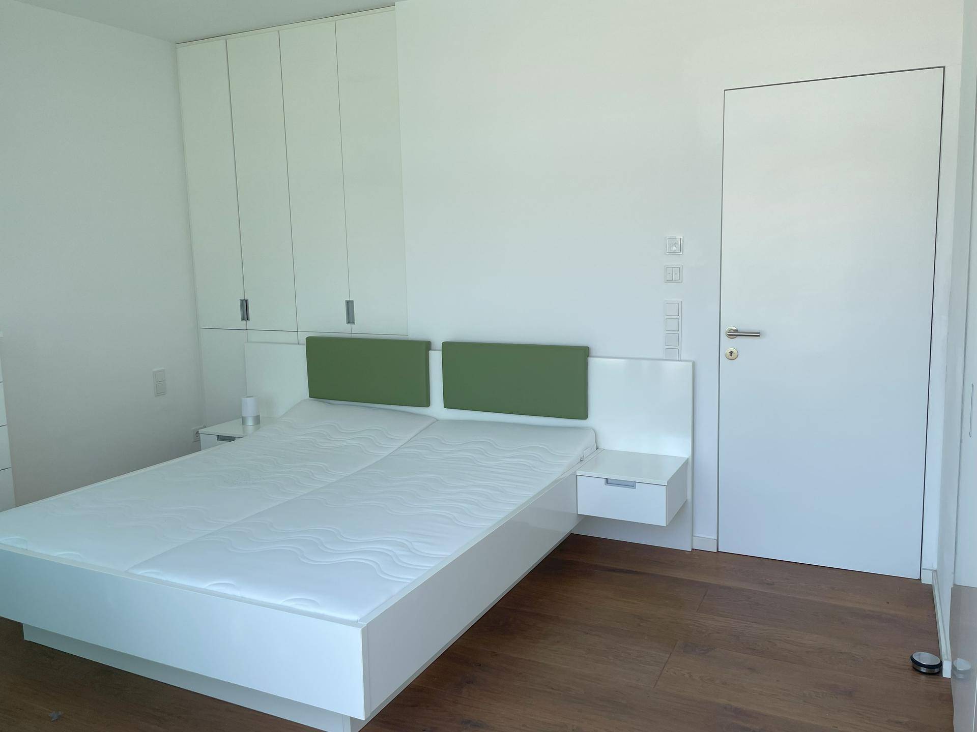 Schlafzimmer mit Einbauschränken, modernem Bett und weißer Tür.