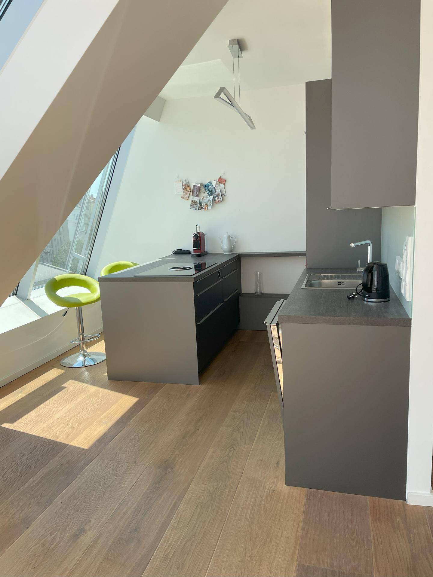 Moderne Küche mit grauen Schränken, Spüle und Barhocker.