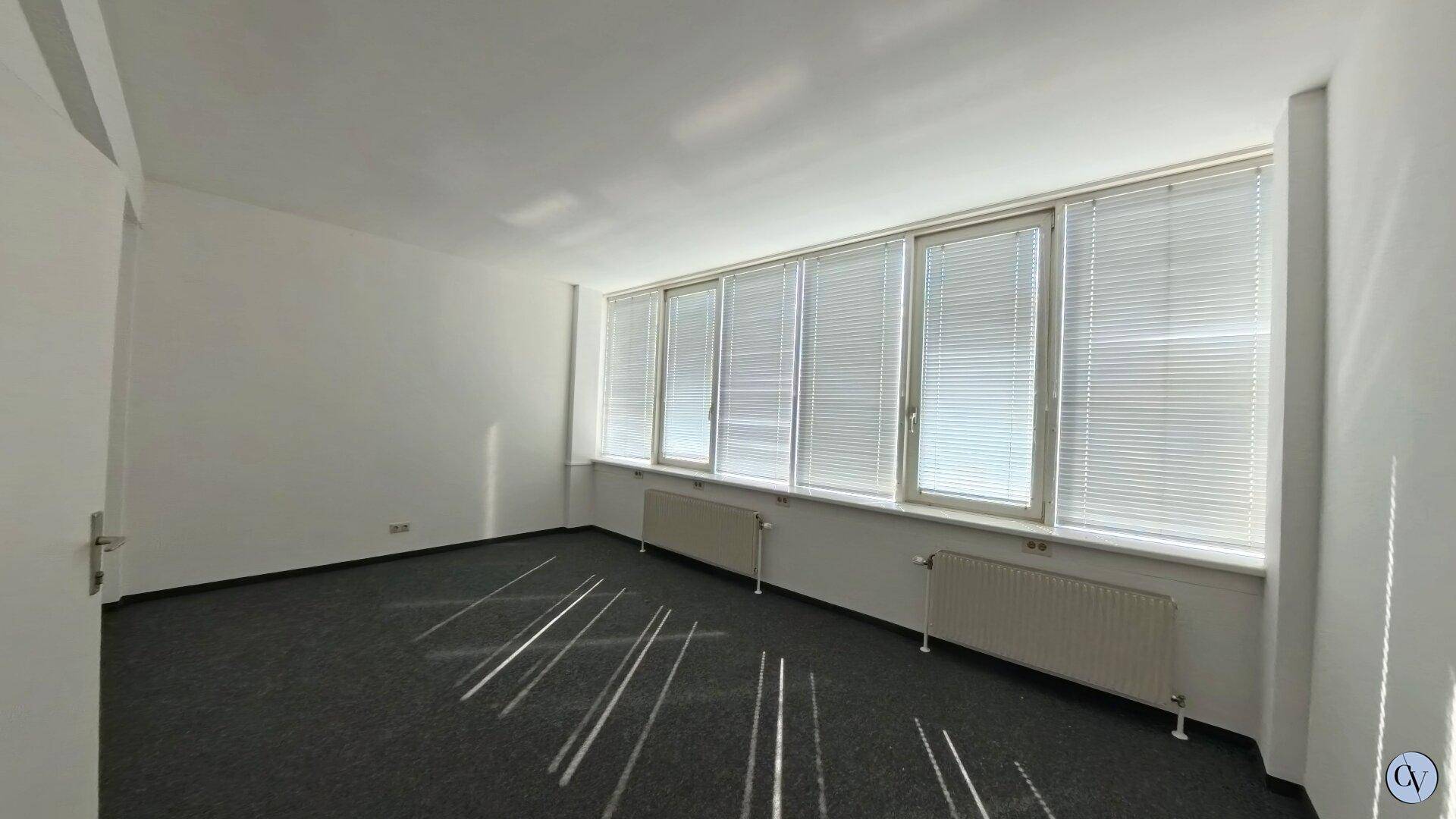 Büroraum mit Fensterfront, ausgestattet mit Jalousien für Privatsphäre und Sonnenschutz, sowie Heizkörpern.