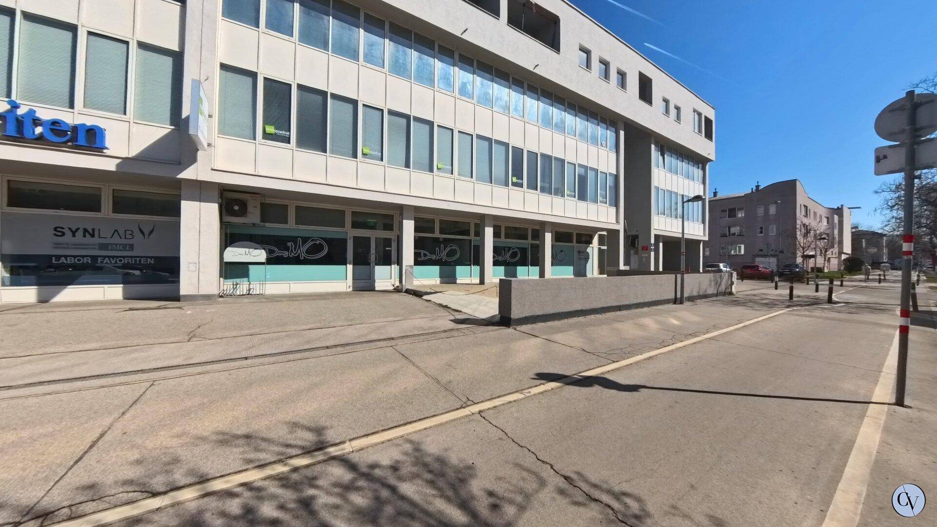 Moderne Geschäftsfassade mit großen Fenstern und einer Rampe für barrierefreien Zugang von der Straße.